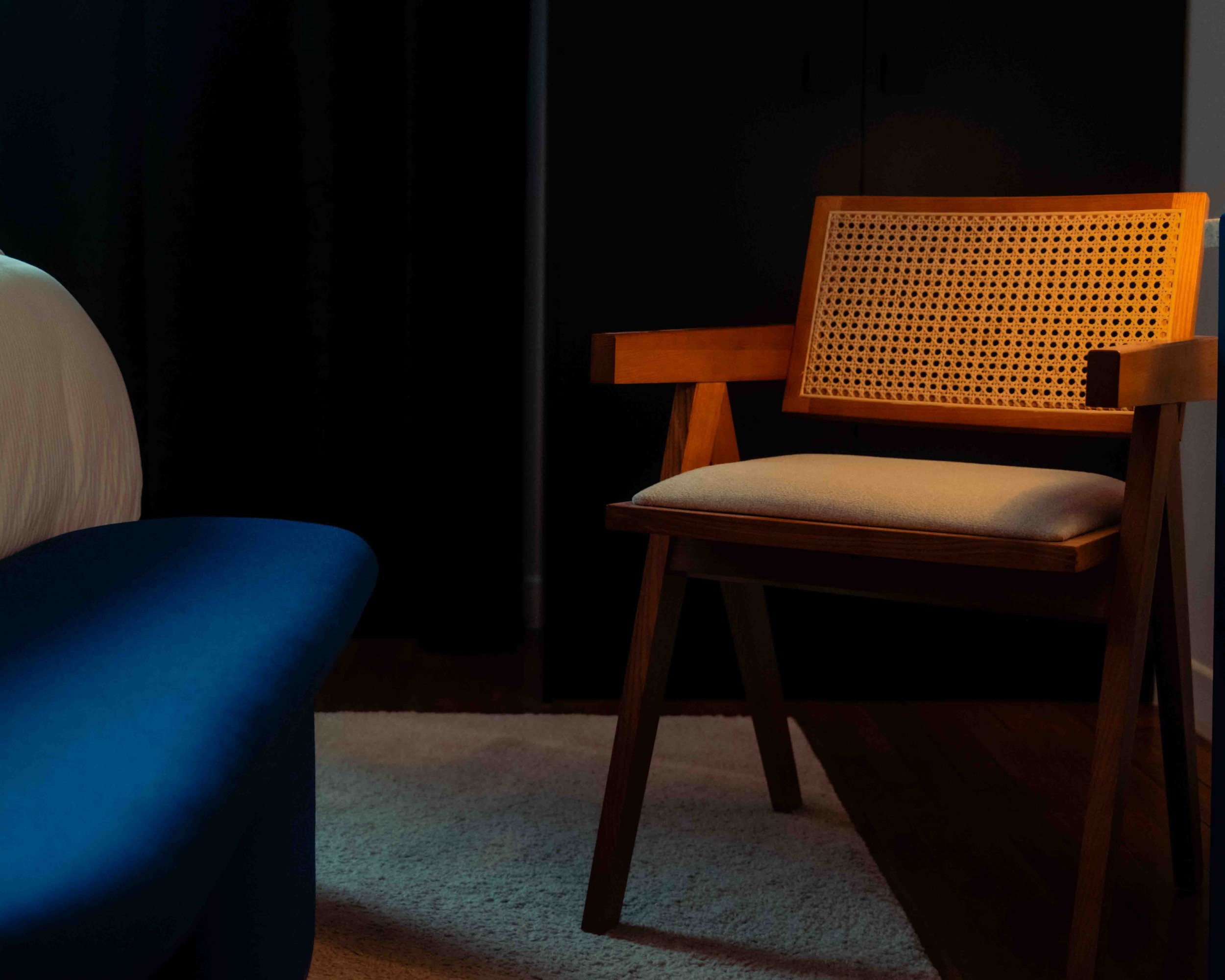 photo d'une chambre, plan rapproché qui met en avant la lumière sur une chaise en cannage et un banc bleu