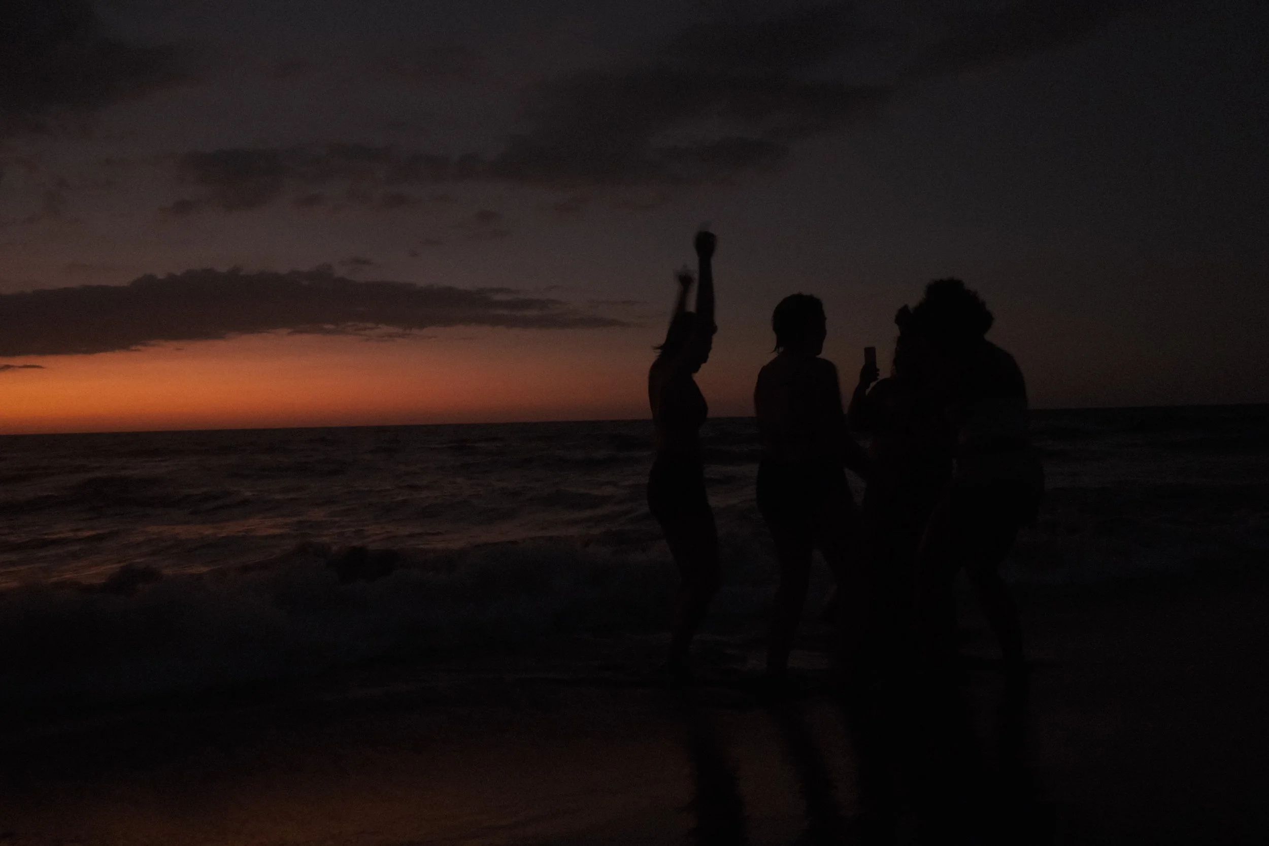 A photo, taken during one of Sonia's yoga retreats, of a person moving in front of a sunset at the beach.