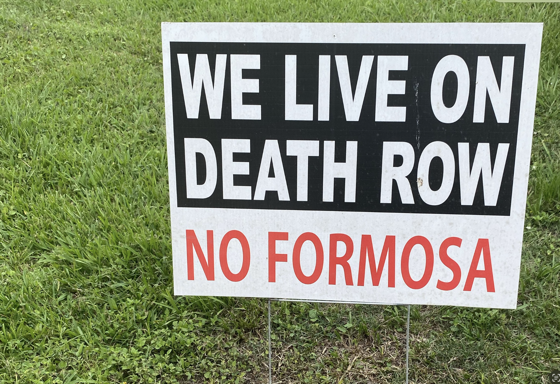 Signboard with text in English and Spanish, placed on grass