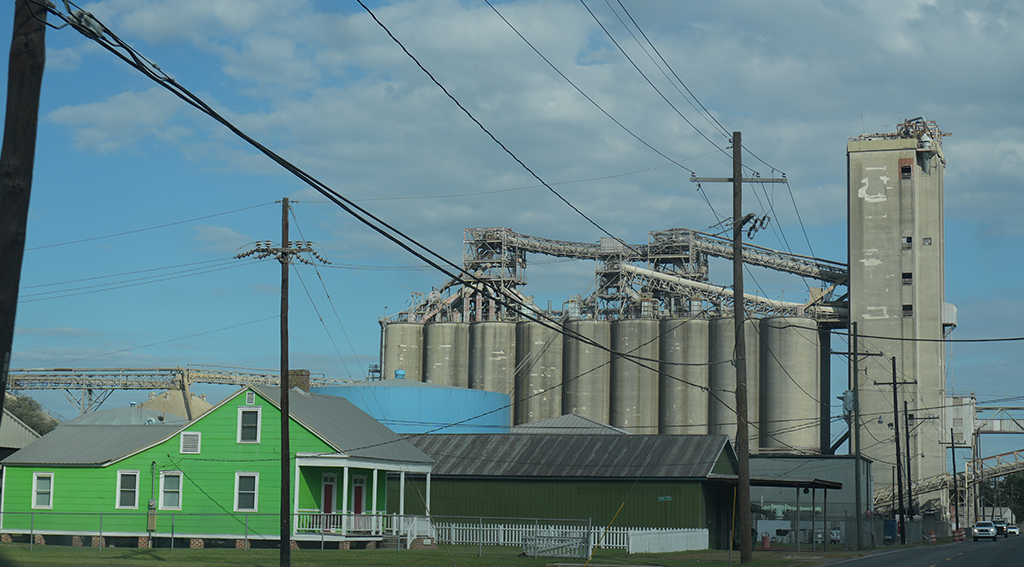 A gray concrete industrial plan towers over a residential home.