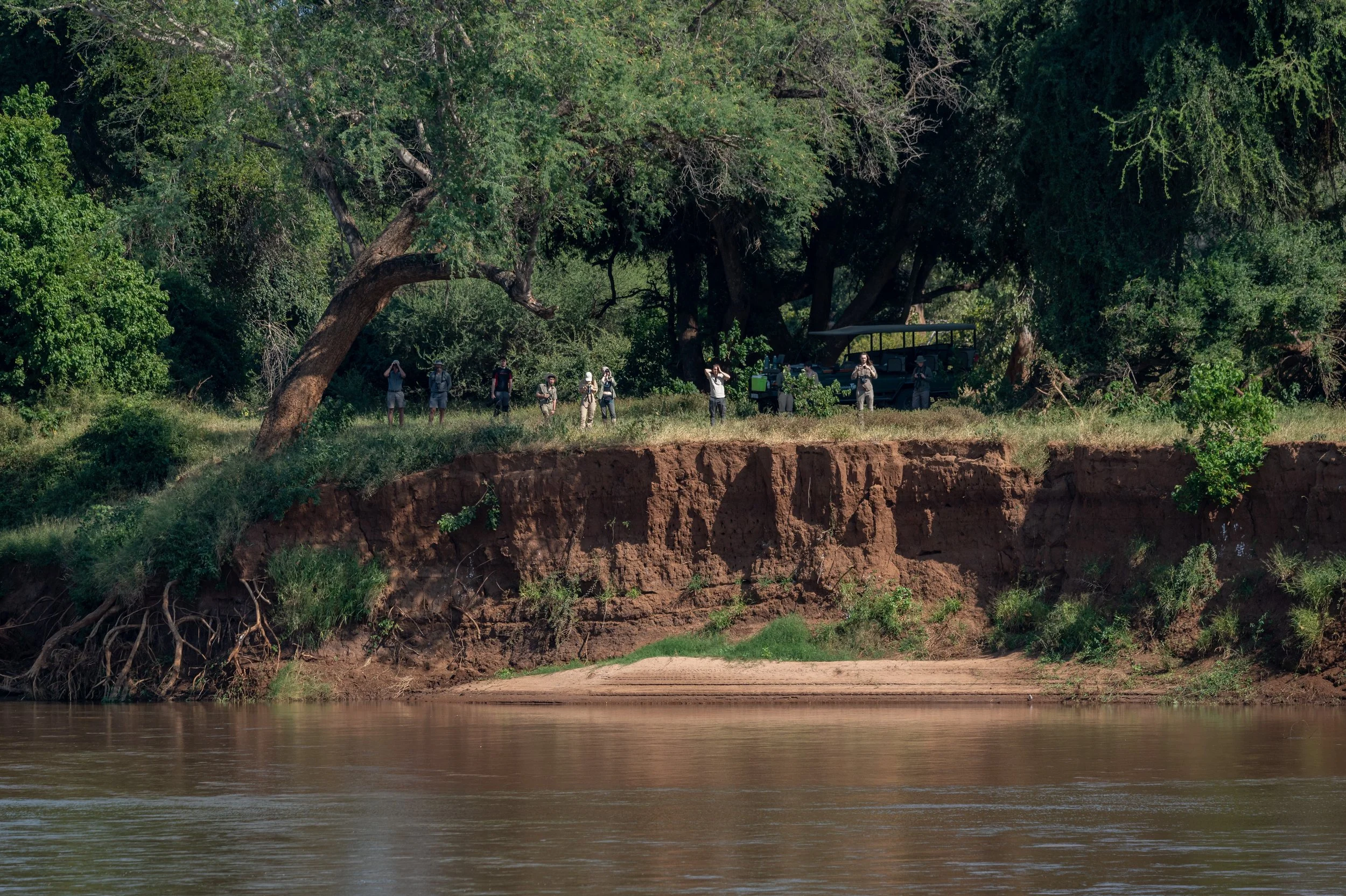 A group of people exploring the riverbank of the Luvuvhu river. Coffe break during a game drive in the remote Makuleke connection of northern Krüger national park, South Africa.