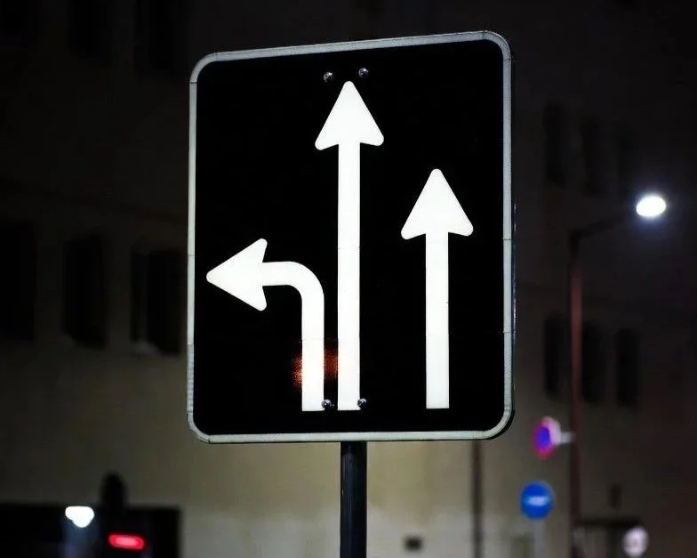 Panneau directionnel visible de nuit montrant les voies de circulation en milieu urbain 