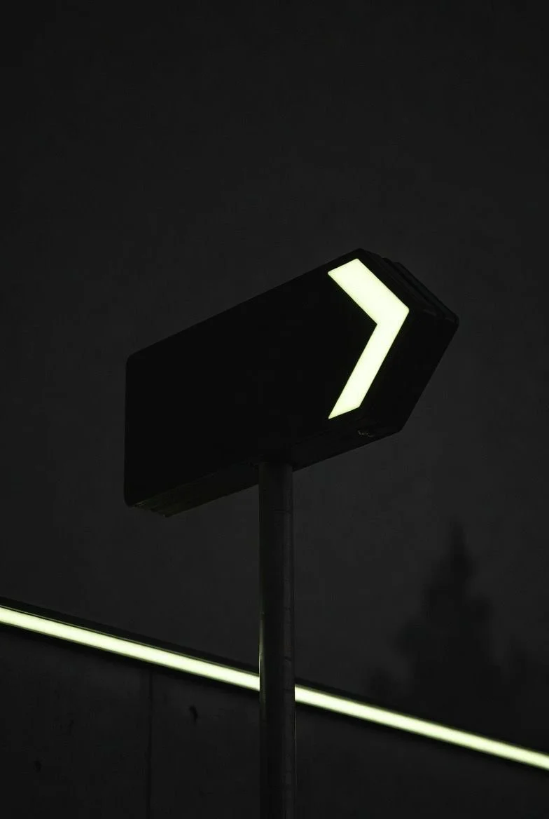 Panneau noir avec flèche lumineuse indiquant la direction dans un environnement sombre