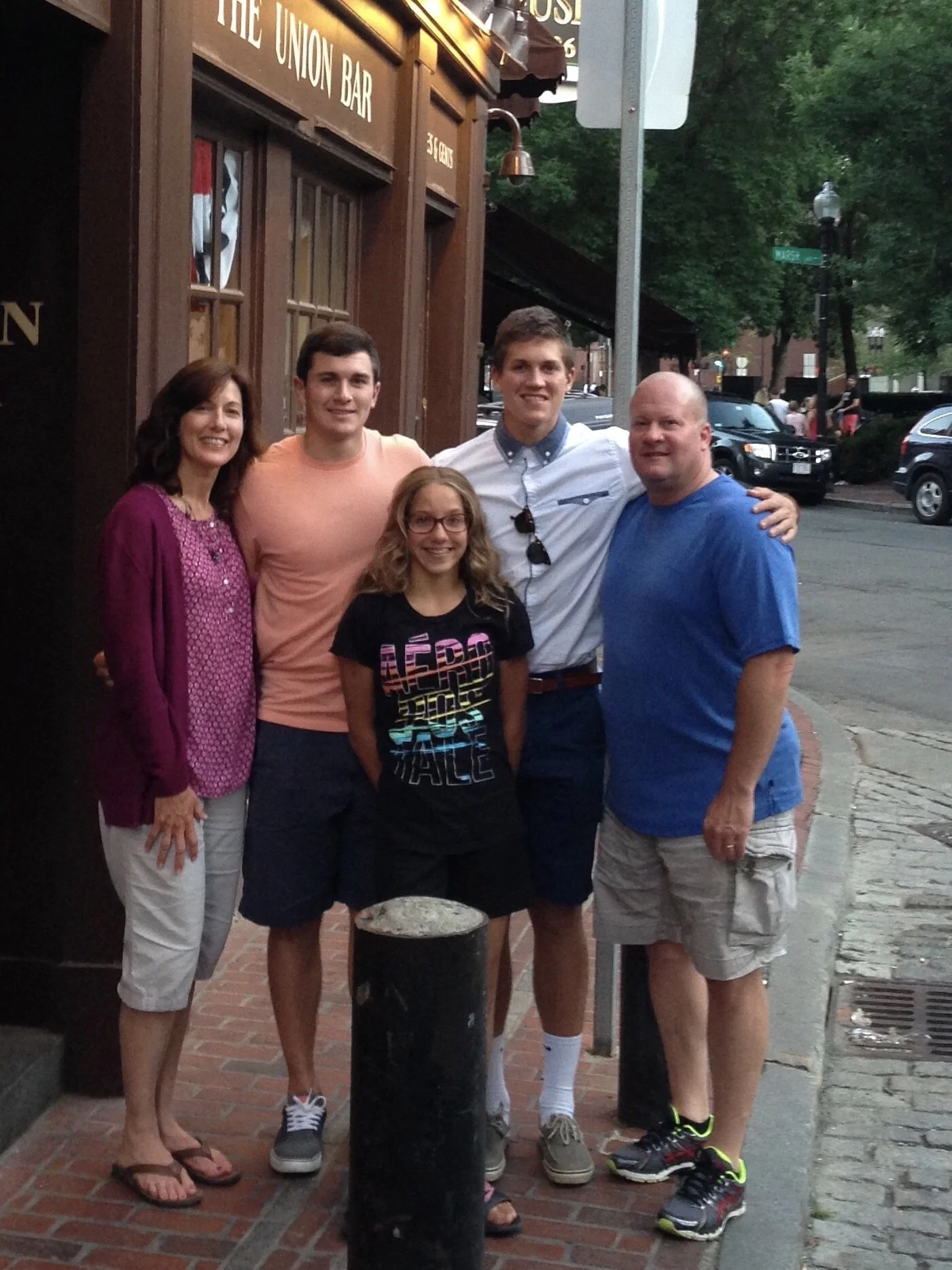 Five people, two women and three men, standing on a sidewalk in front of a bar called The Union Bar, smiling for a group photo.