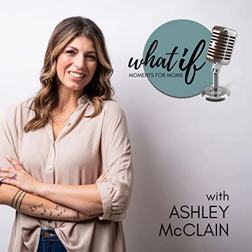 A woman with long brown hair smiling and crossing her arms, standing in front of a white wall with a logo and microphone graphic that reads 'what if moments for moms' and 'with Ashley McClain' Episode featuring Author Debbie Prather