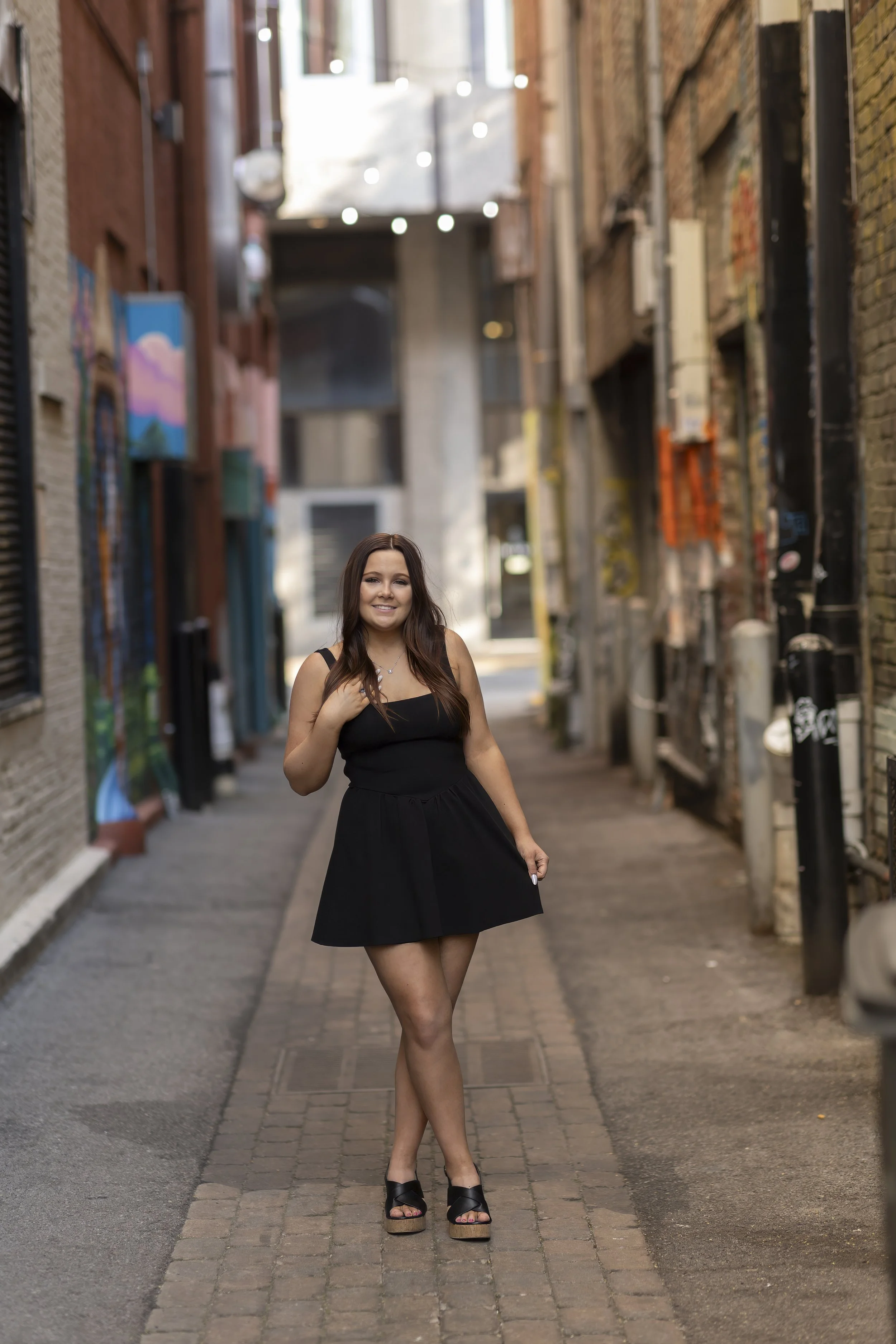 High school senior in a black dress posing in an urban alley in downtown Knoxville, Tennessee.