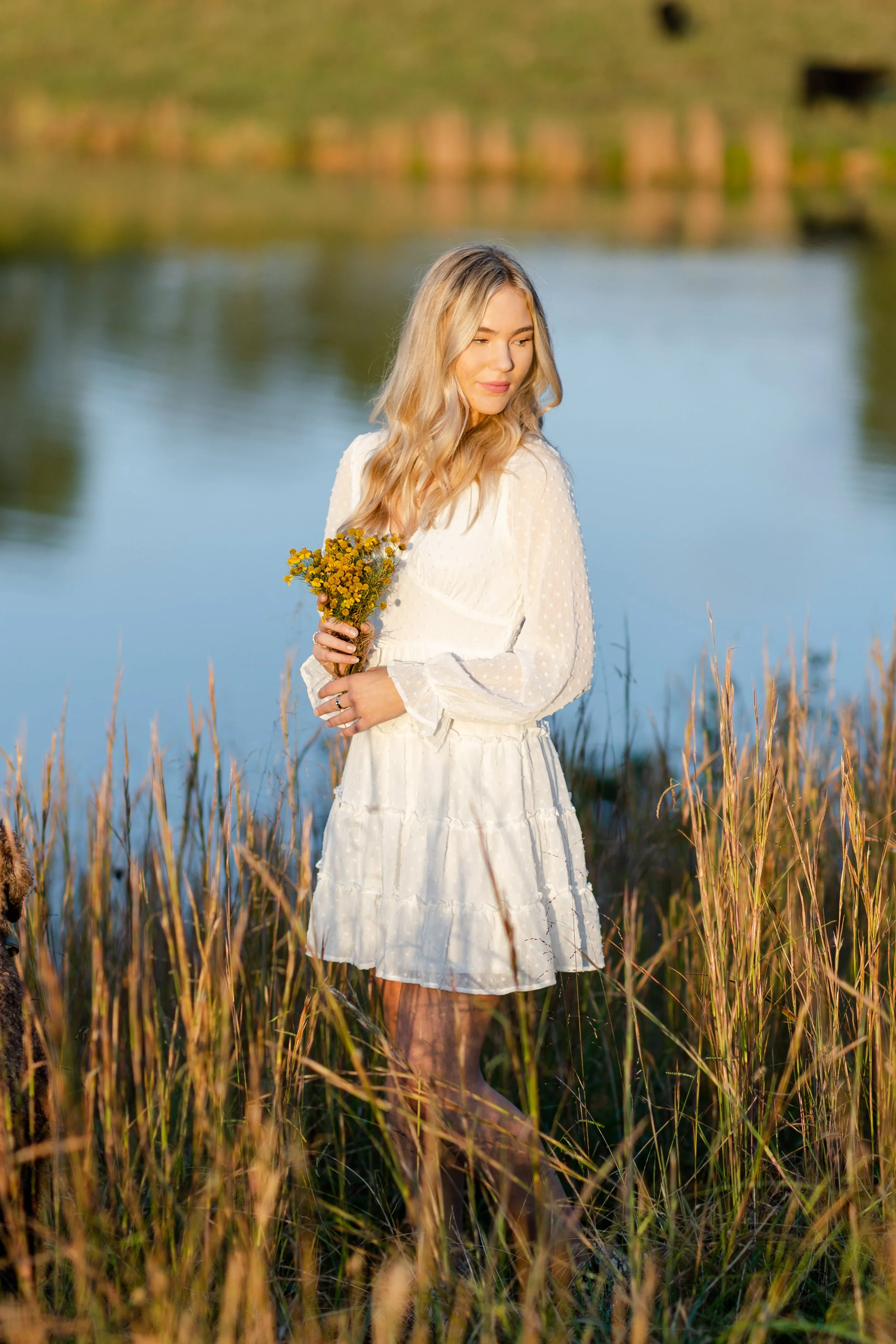 High school senior in a white dress beside the pond at Strong Stock Farm in Knoxville, Tennessee.