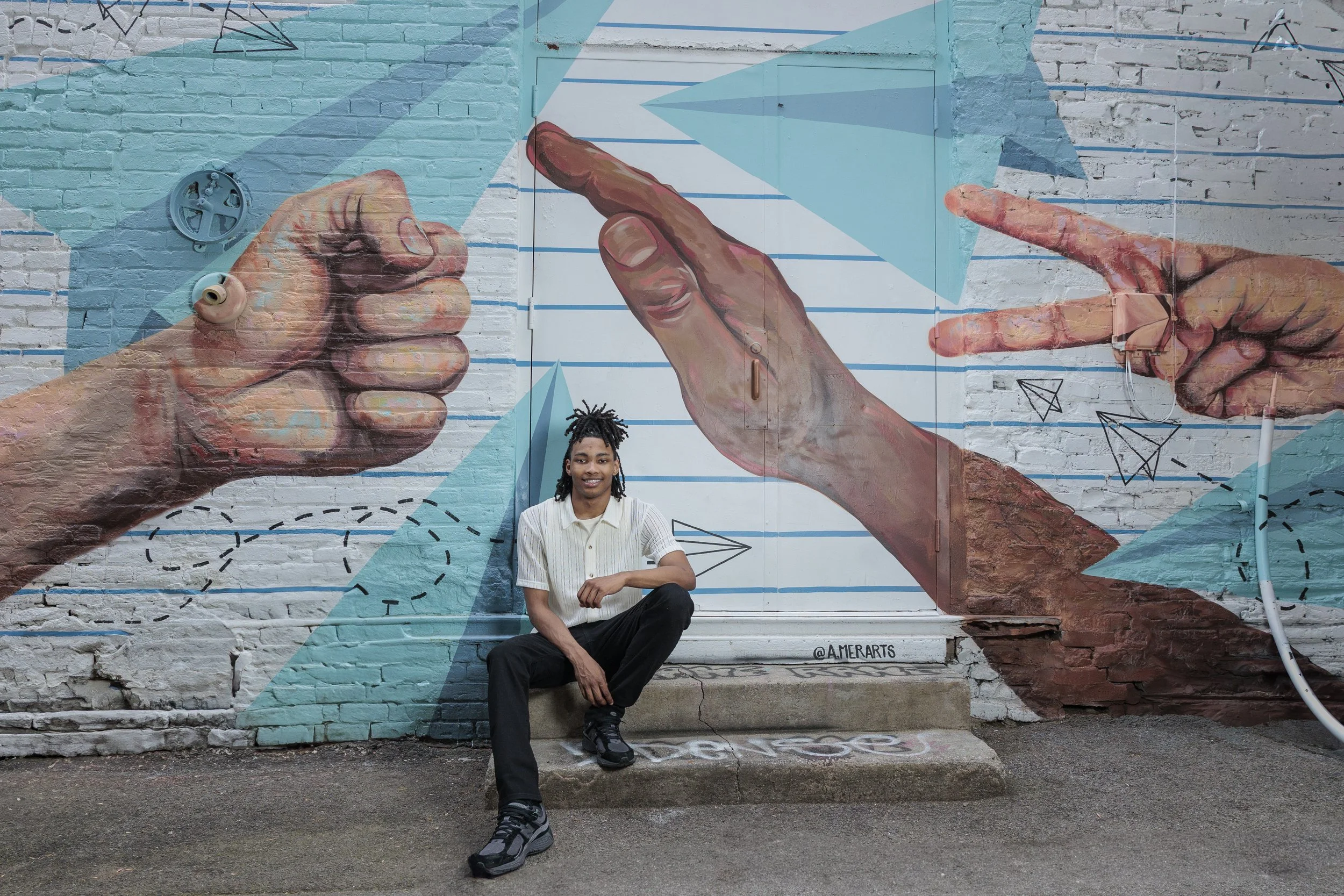 Knoxville high school senior seated in front of a colorful downtown mural during his senior portrait session.