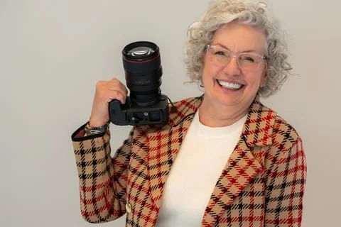 Amy Melendy, Knoxville family and senior photographer, smiling while holding her camera.