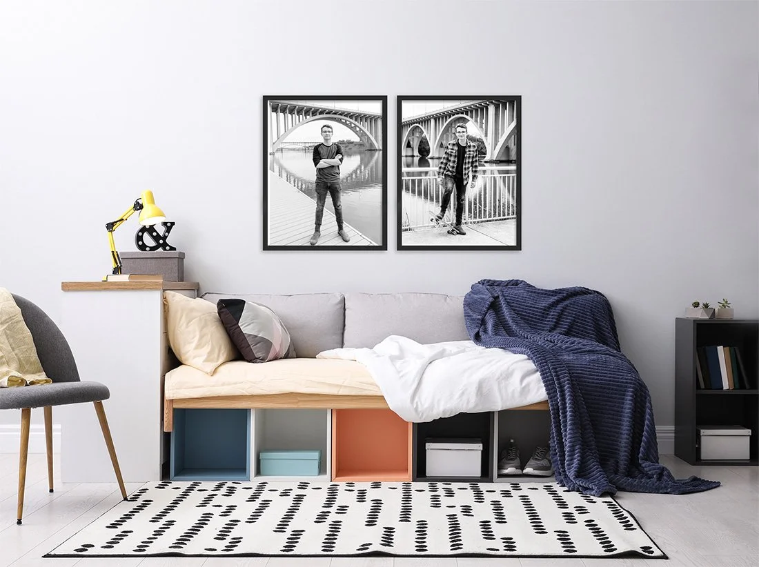 Two black-and-white senior portraits displayed as framed wall art in a bedroom.