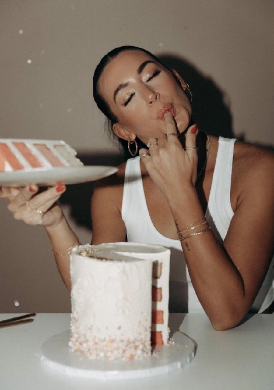 best kitchenaid attachment for frosting - a woman sitting with a slice of cake licking frosting off her finger
