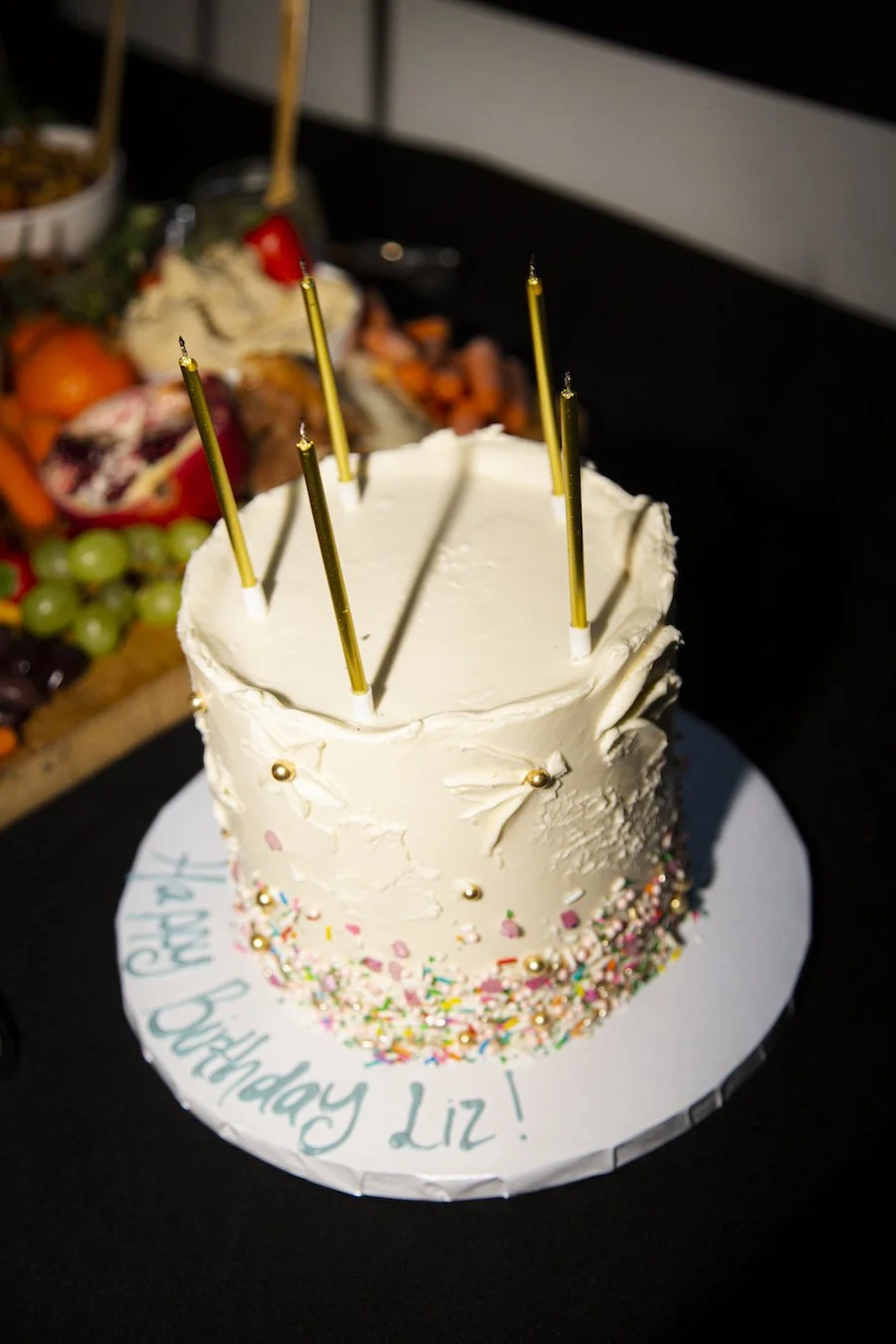 fondant vs buttercream birthday cake - white cake decorated with sprinkles around the bottom and gold candles