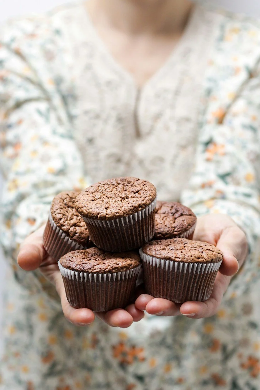 what to substitute for vegetable oil in cake mix - a woman holding a stack of baked cupcakes