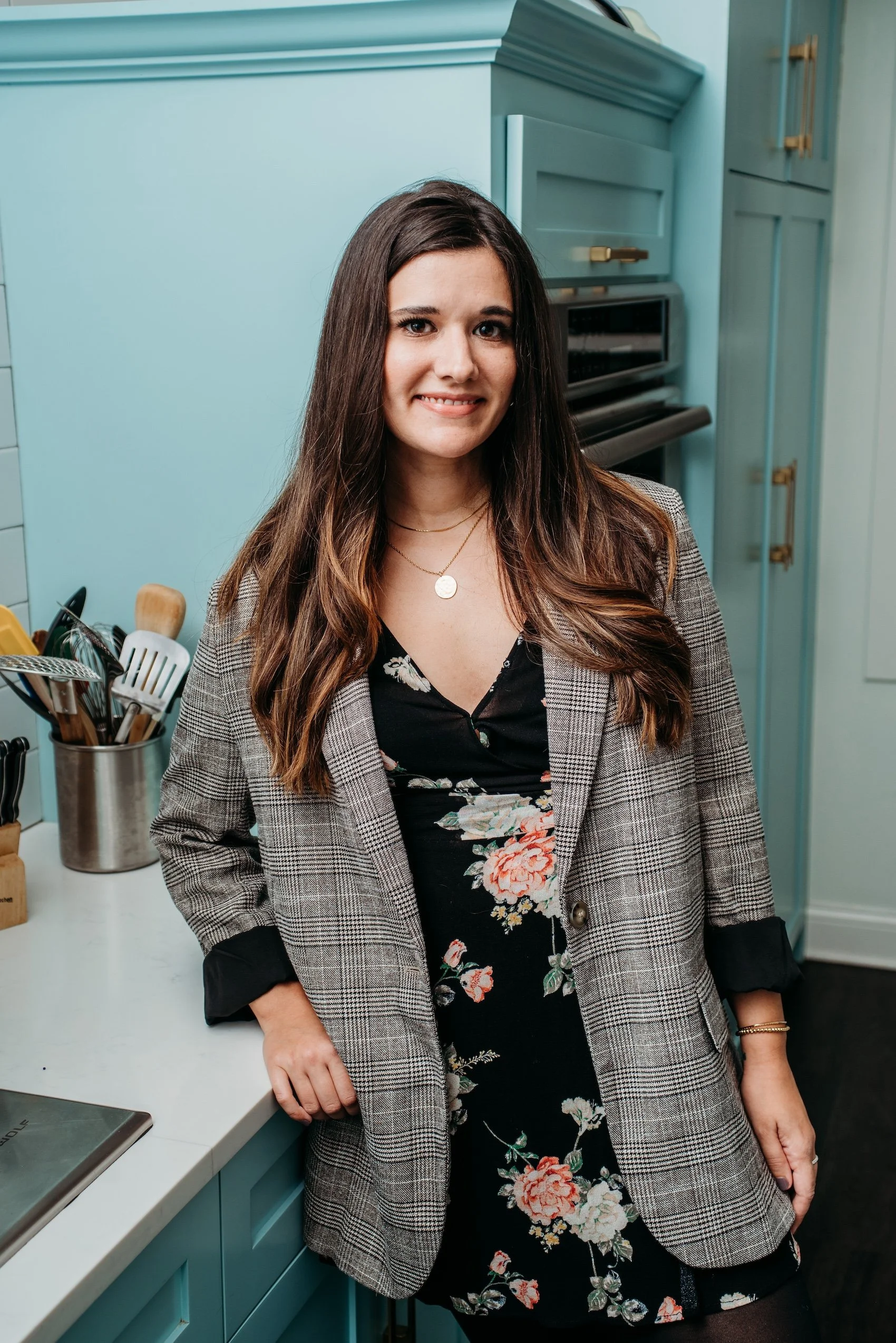 Headshot of ECBG Studio's team member, Kelly, smiling in plaid blazer and floral top