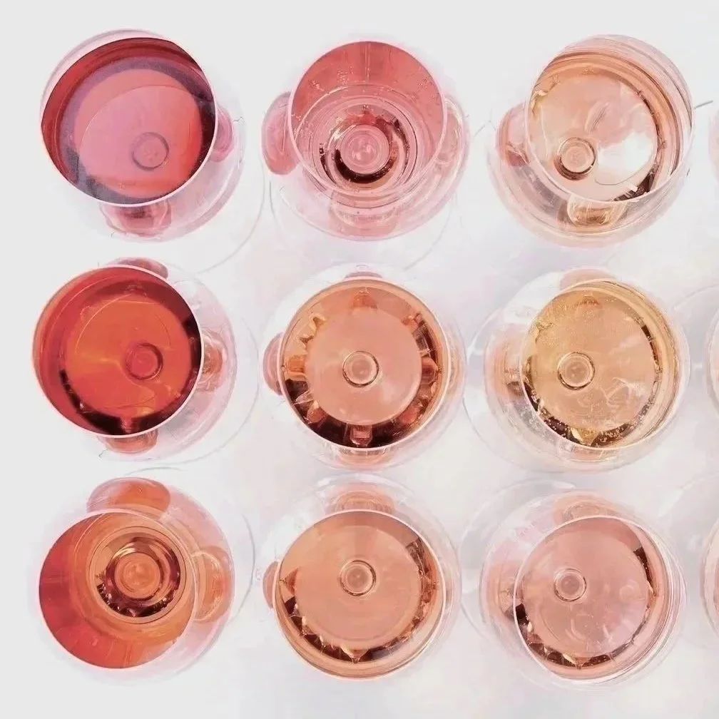 Top view of nine glasses of pink or rose wine arranged in a 3x3 grid on a white surface.
