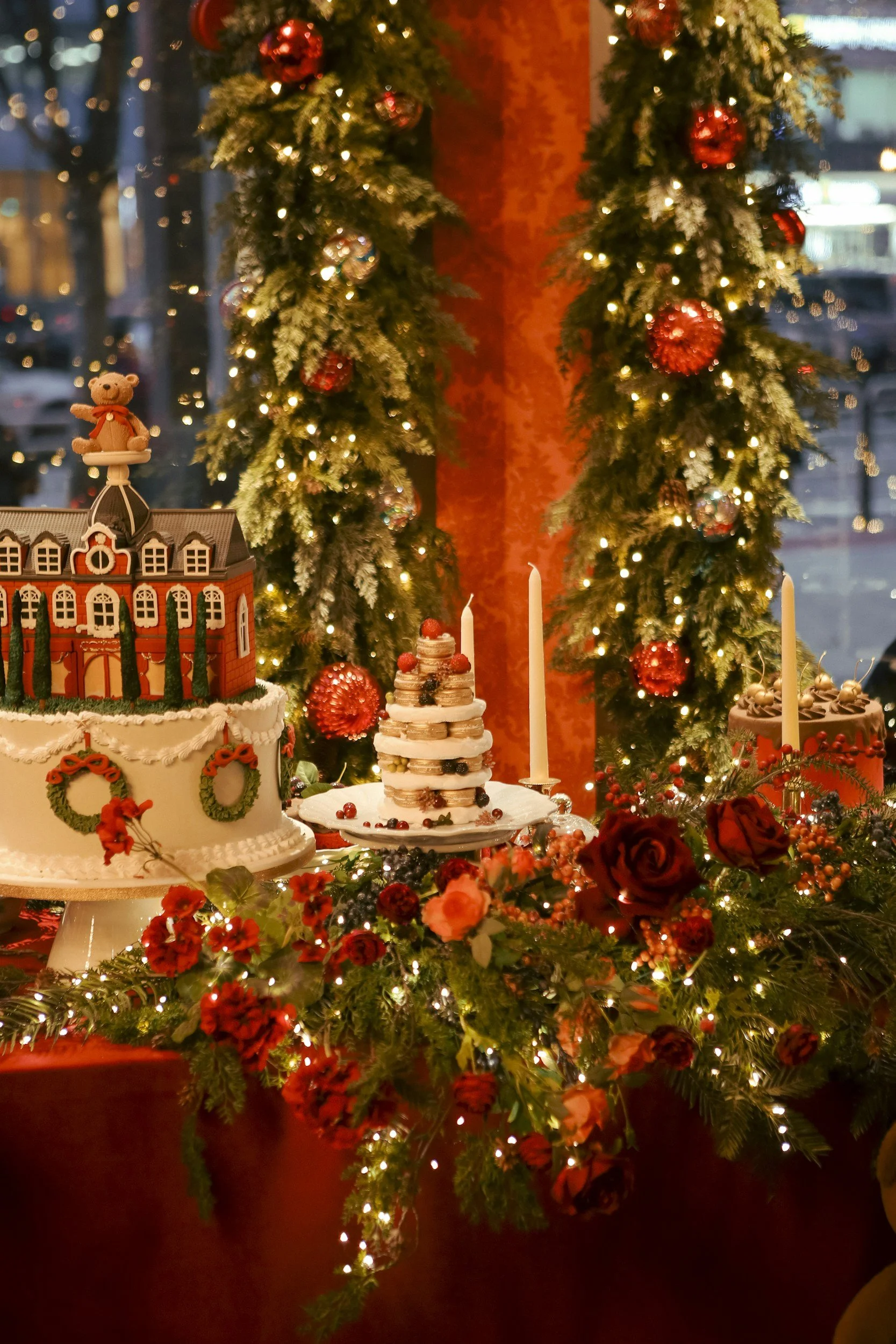 Christmas decorated table with cakes, flowers, candles, and garlands, with Christmas trees in the background