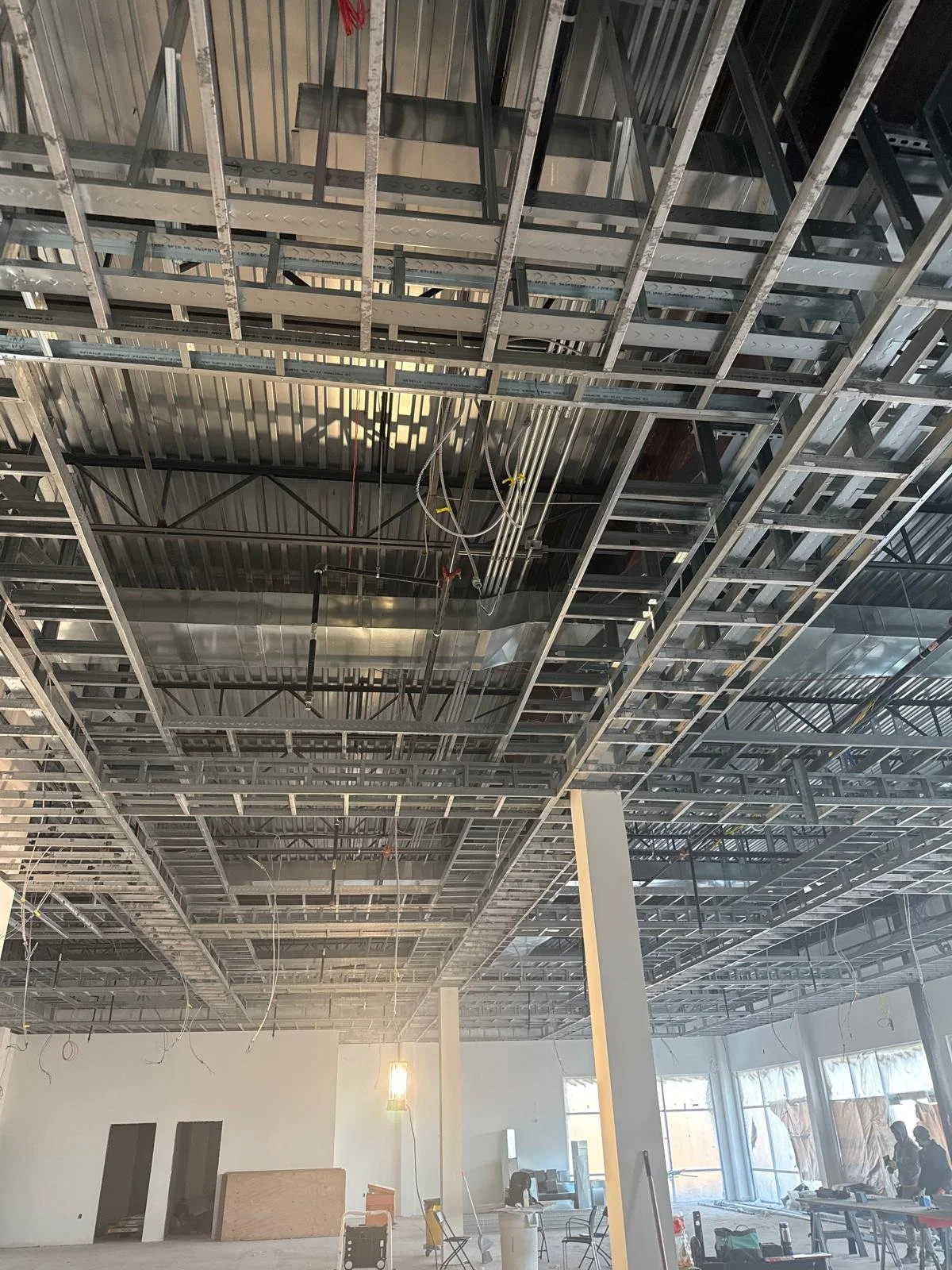 Interior of a building under construction with metal framing on the ceiling and partially finished walls.