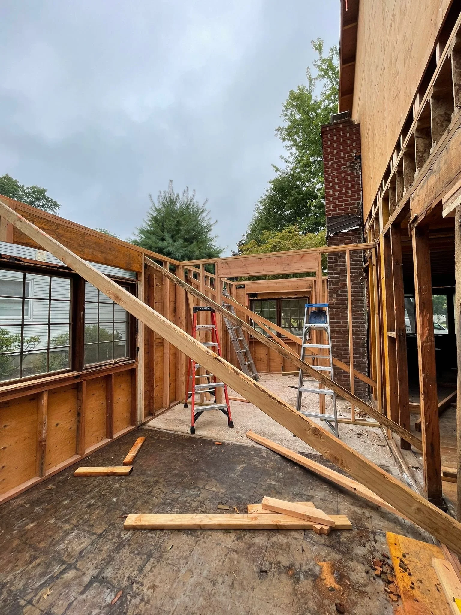 Construction site of a porch or deck with wooden framing and ladders during building process.