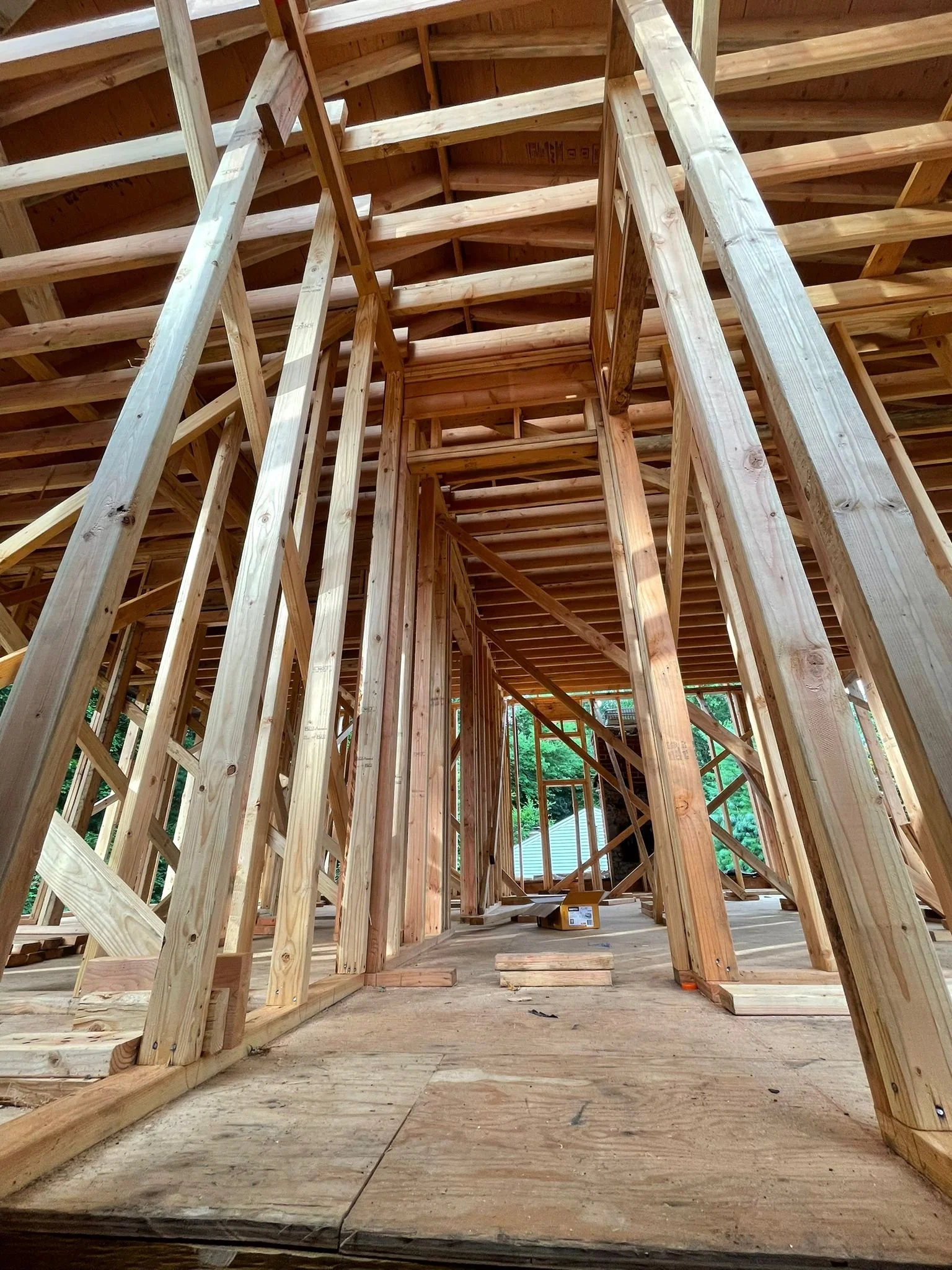 Interior view of a house under construction with visible wooden framing and support beams.