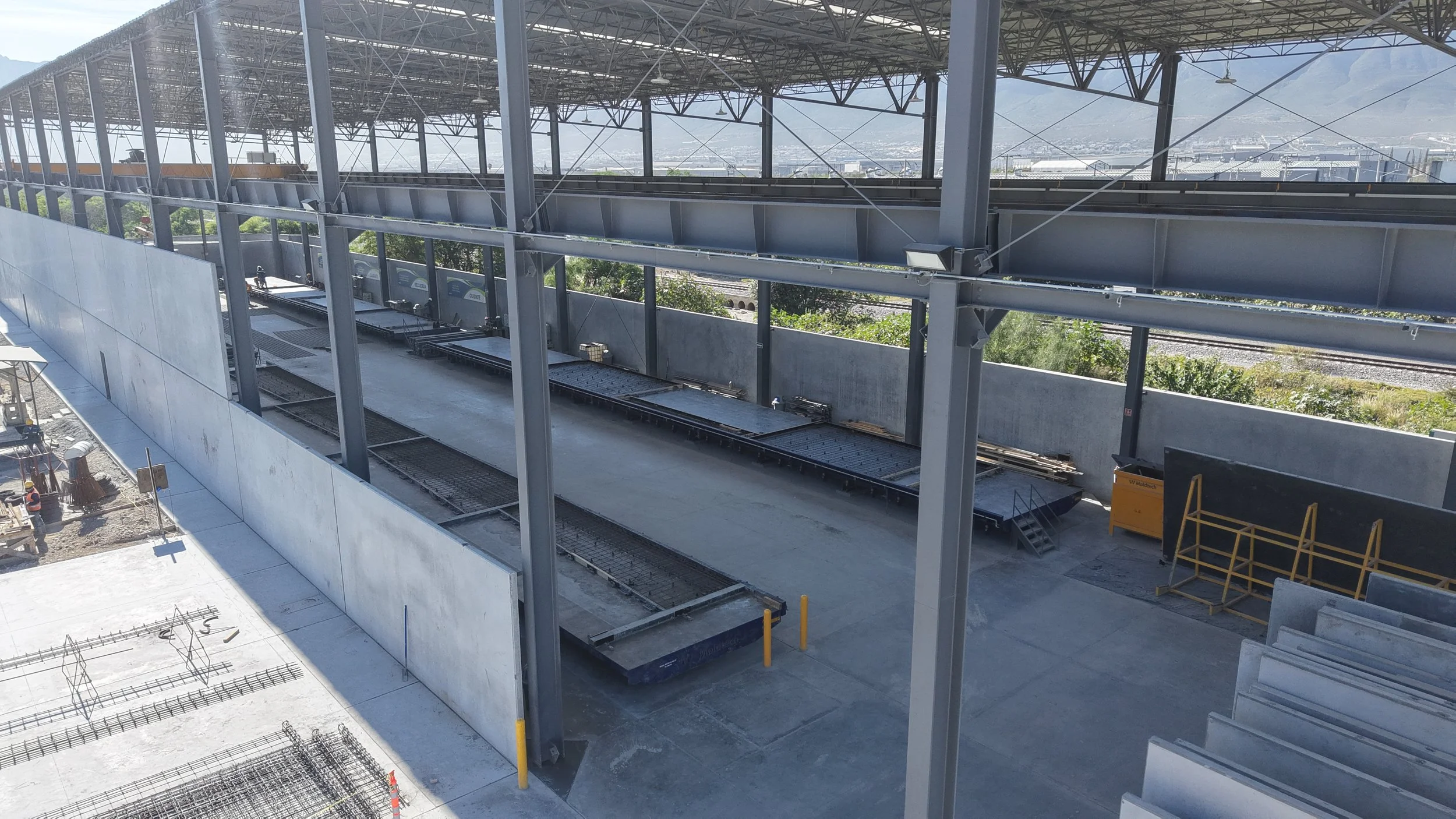 Construction site with steel framework, concrete platform, and equipment for building a transportation station or similar structure.