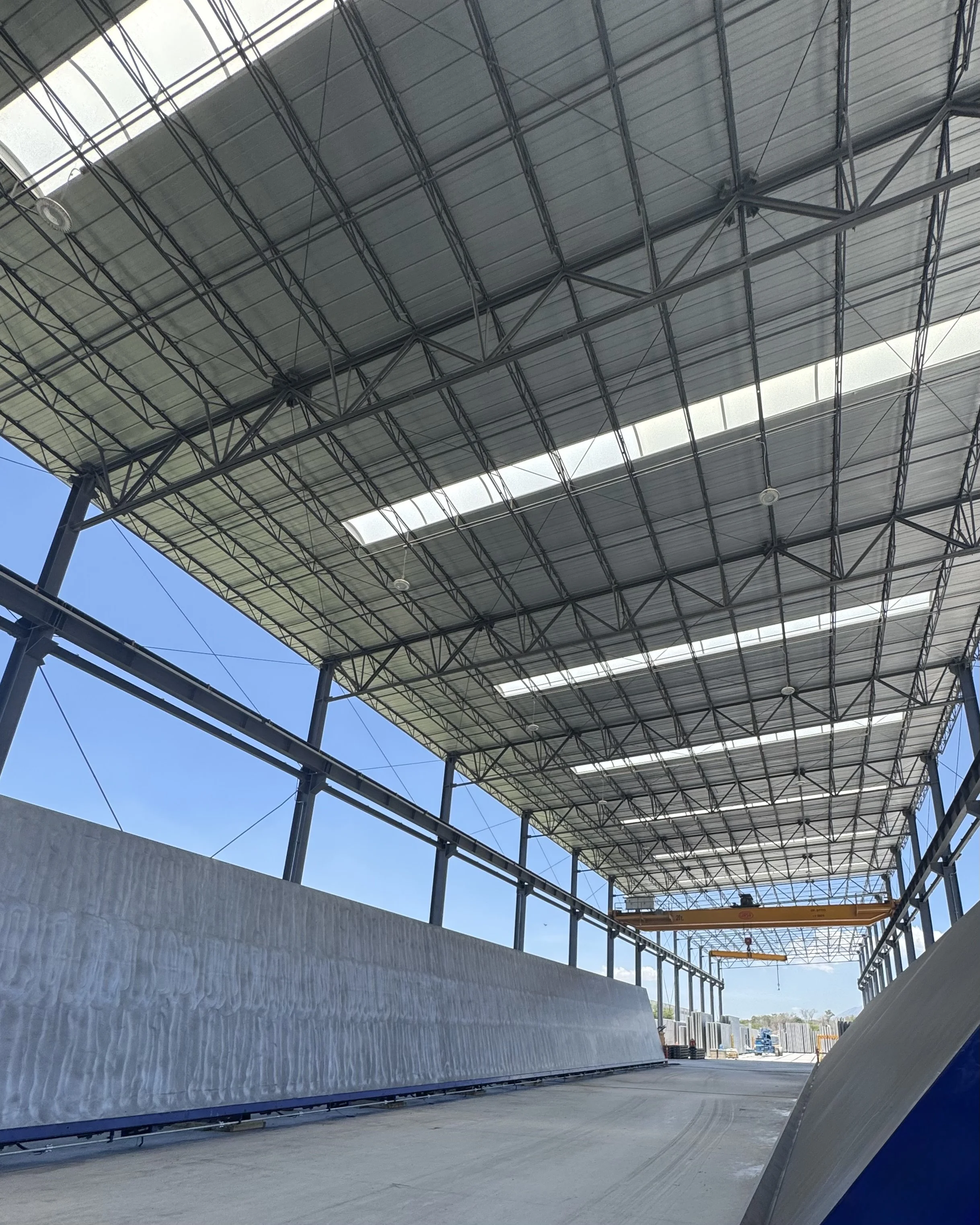 Estructura de techado en construcción en una vía, con mesas basculantes y estructuras metálicas, cielo despejado.