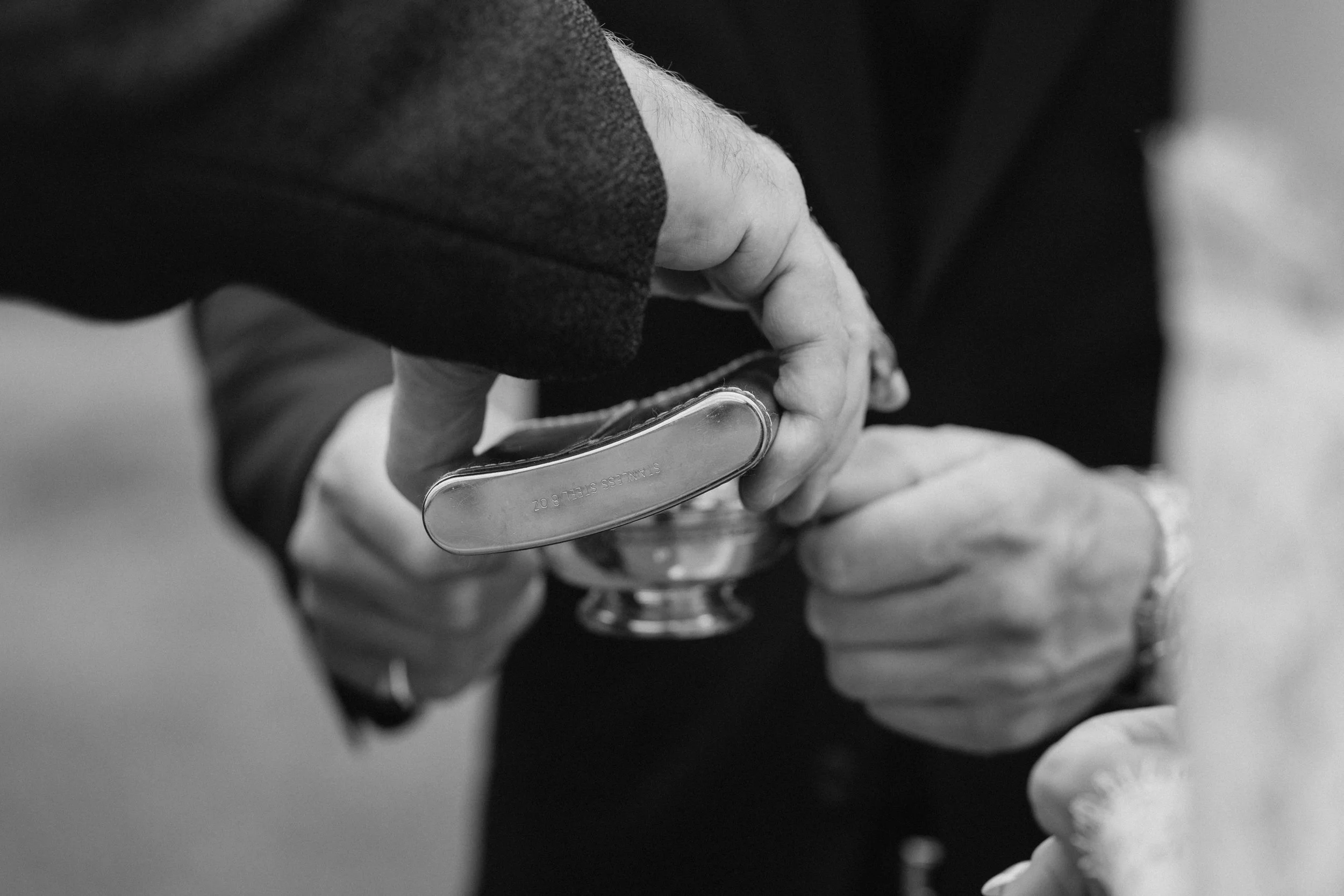 Close-up of two hands, one holding a money clip and the other reaching to exchange money, in a black and white photo. - captured by an Edinburgh wedding photographer