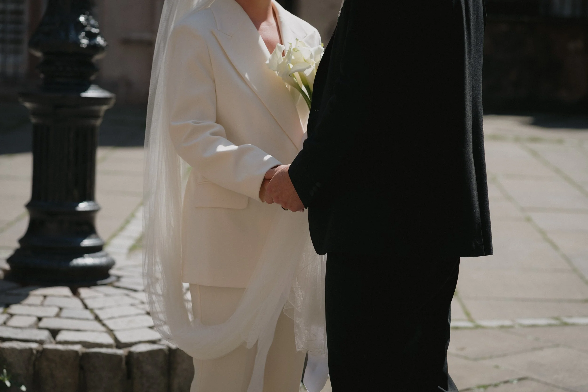 Close-up of a bride and groom holding hands during a wedding ceremony outdoors. - captured by an Edinburgh wedding photographer