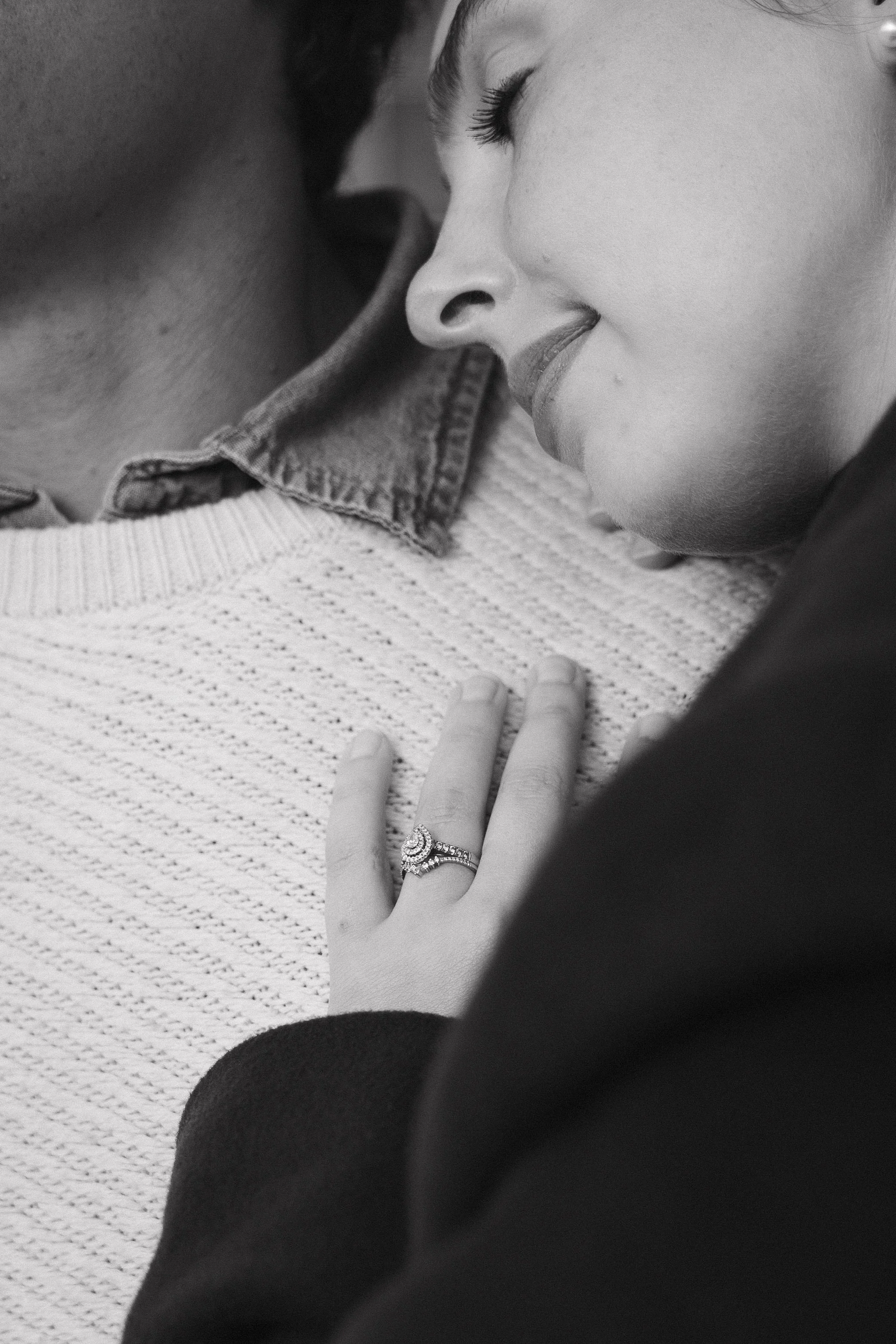 A woman and man with their foreheads touching, the woman smiling with her eyes closed, showing her engagement ring, in black and white. - captured by an Edinburgh wedding photographer