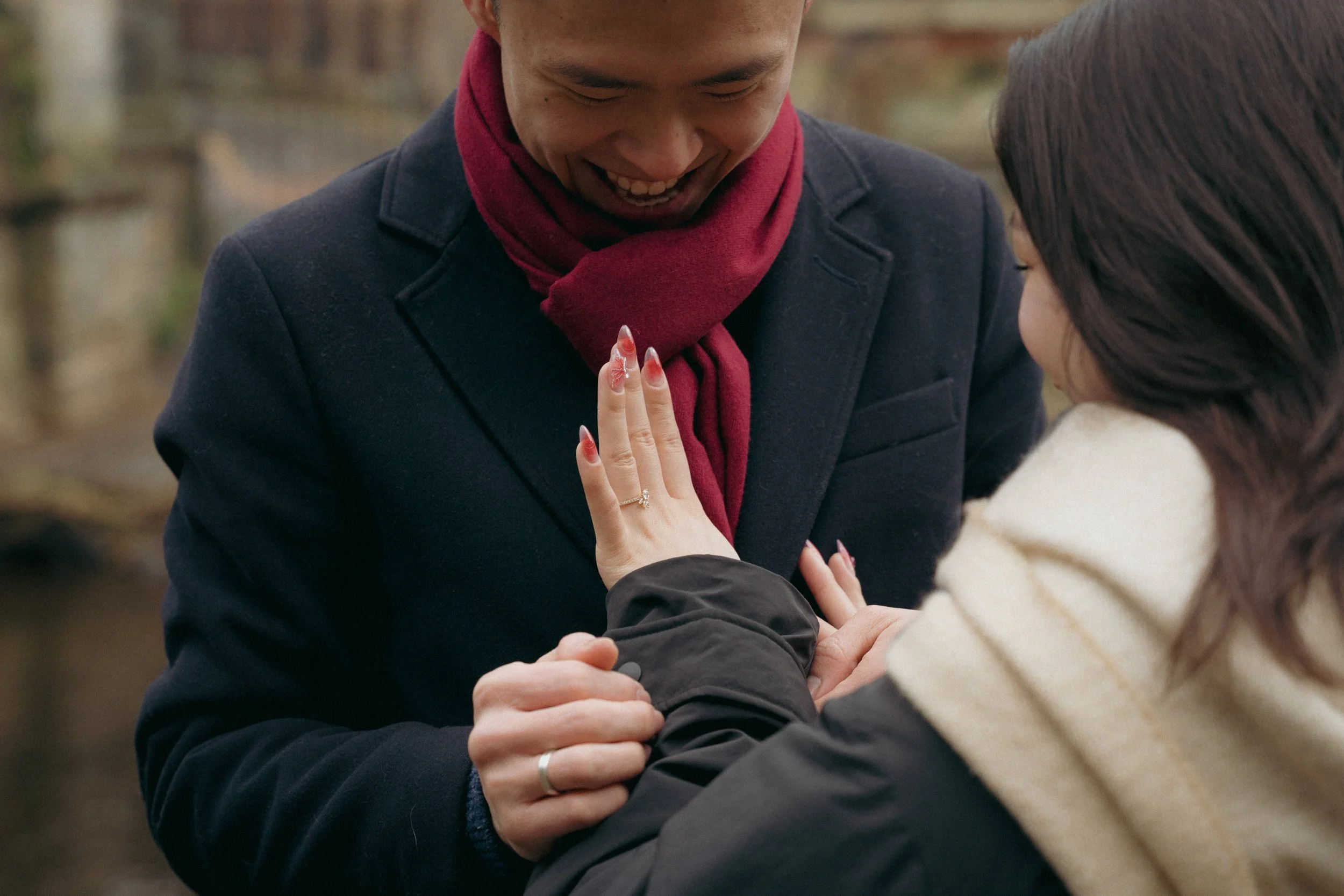 A couple smiling and holding hands during a daytime outdoor moment. - captured by an Edinburgh wedding photographer