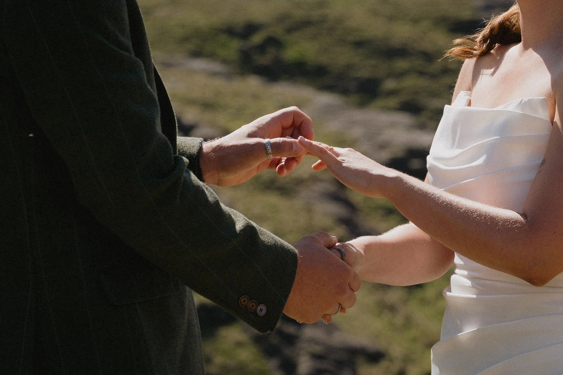 A couple holding hands during a wedding ceremony outdoors, with the focus on their hands and rings. - captured by an Edinburgh wedding photographer