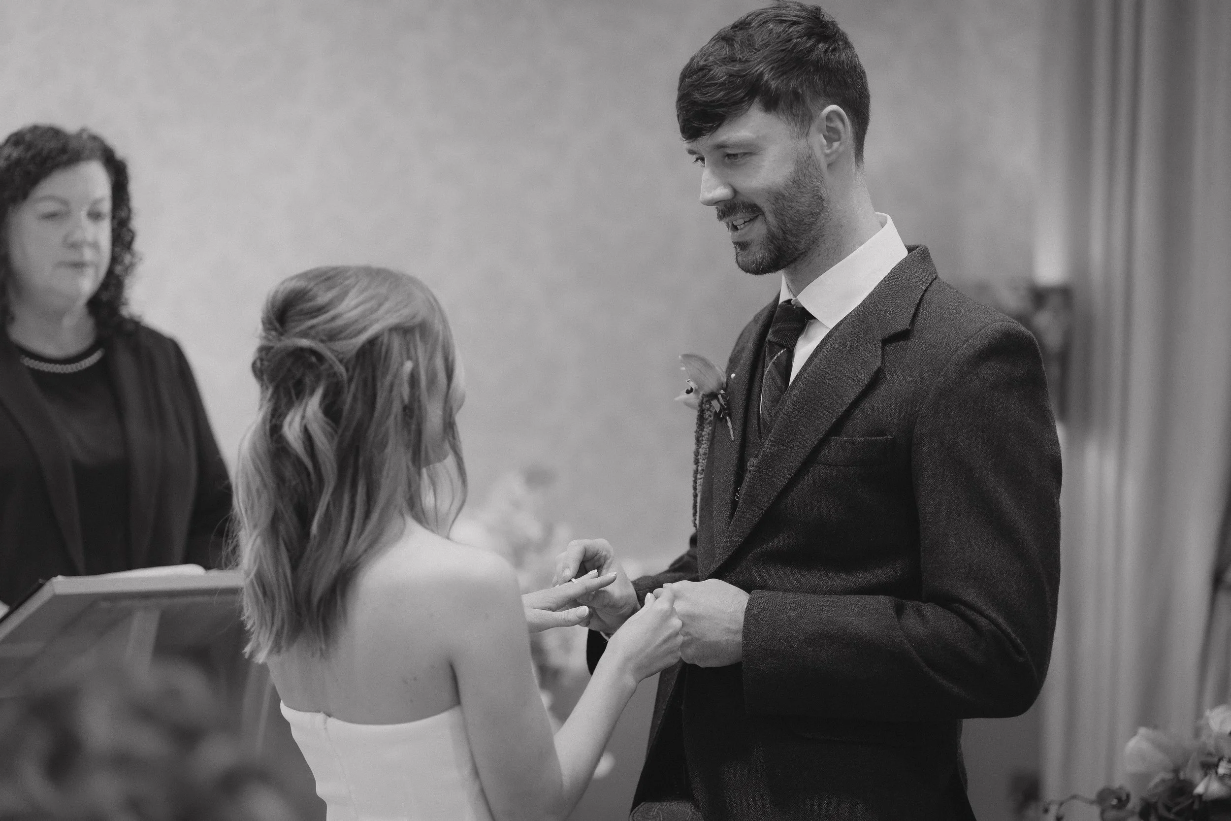 A couple exchanging wedding rings during a wedding ceremony, with an officiant present. - captured by an Edinburgh wedding photographer