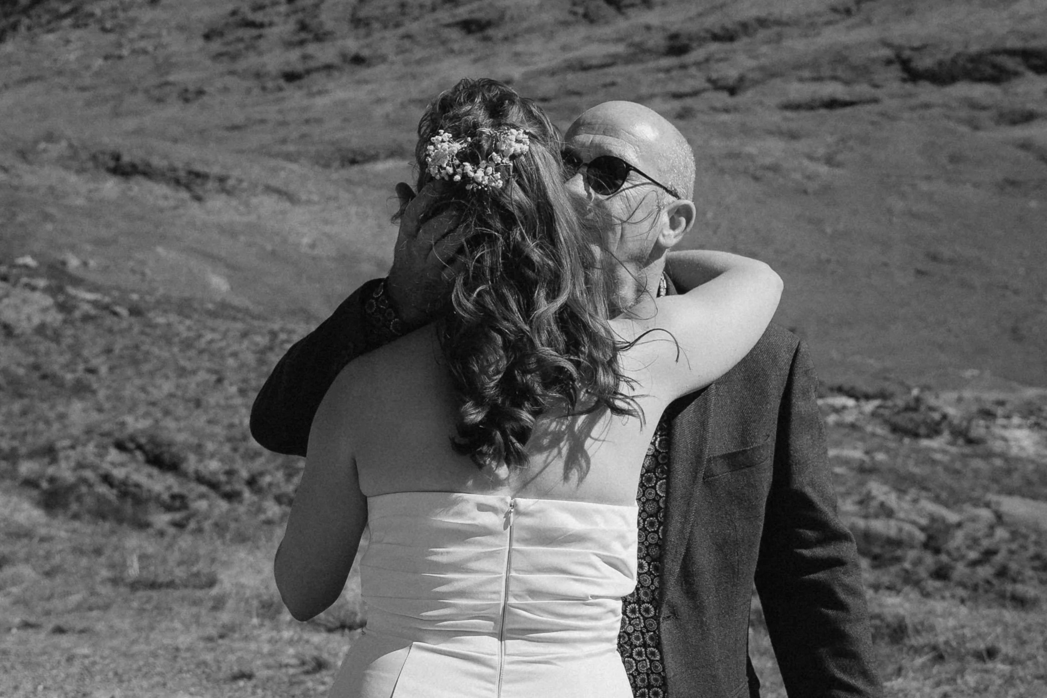 A woman in a strapless dress and a man in a suit embracing and kissing outdoors. - captured by an Edinburgh wedding photographer