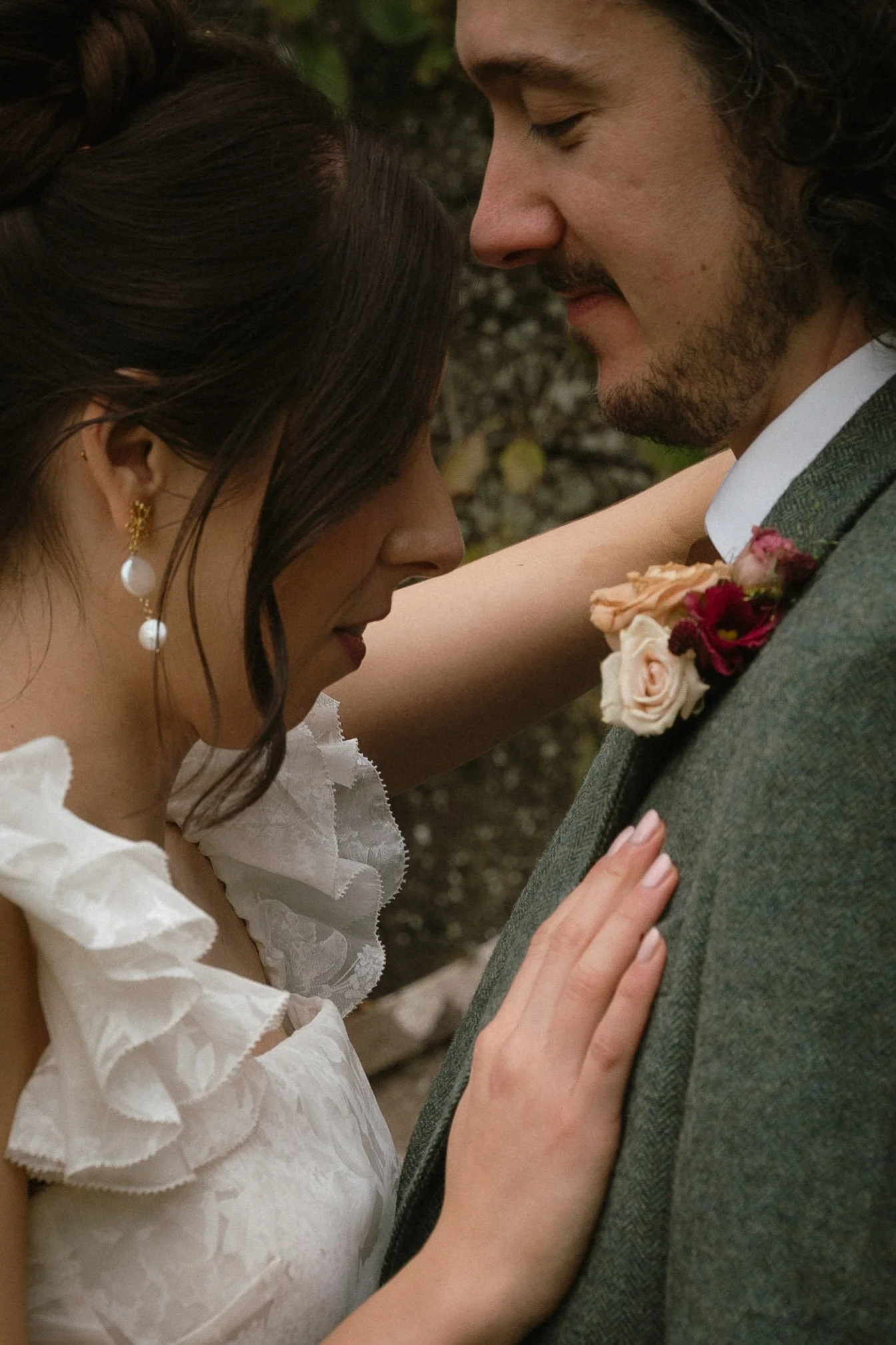A couple dressed in wedding attire, with their foreheads touching and eyes closed, embracing outdoors - captured by an Edinburgh wedding photographer