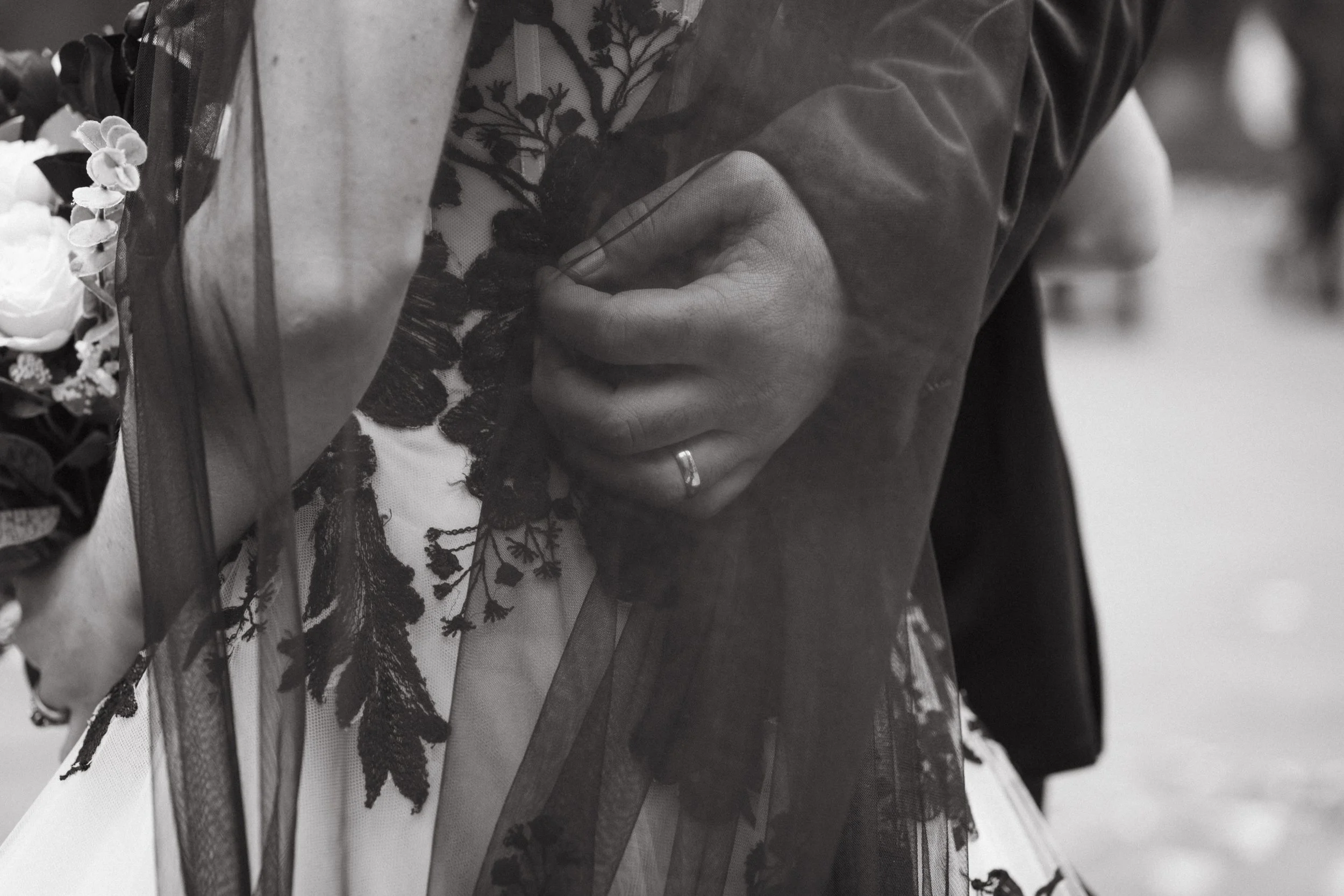 Close-up of a person's hand adjusting a wedding dress with lace detailing, wearing a wedding ring - captured by an Edinburgh wedding photographer