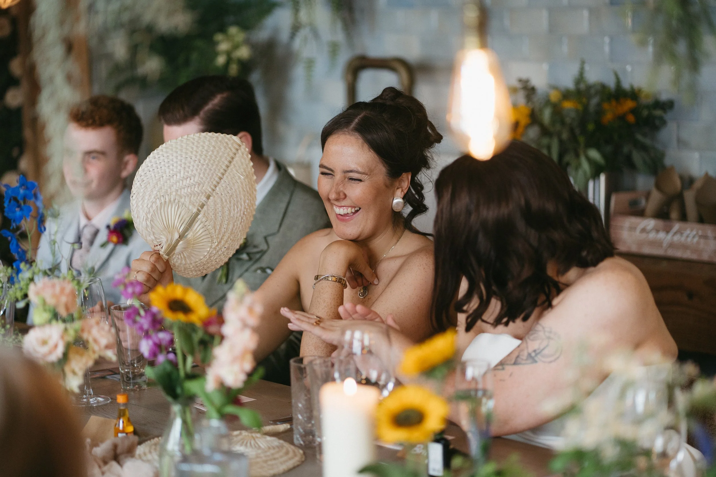 People at a festive gathering, smiling and chatting at a decorated table with flowers and candles. - captured by an Edinburgh wedding photographer