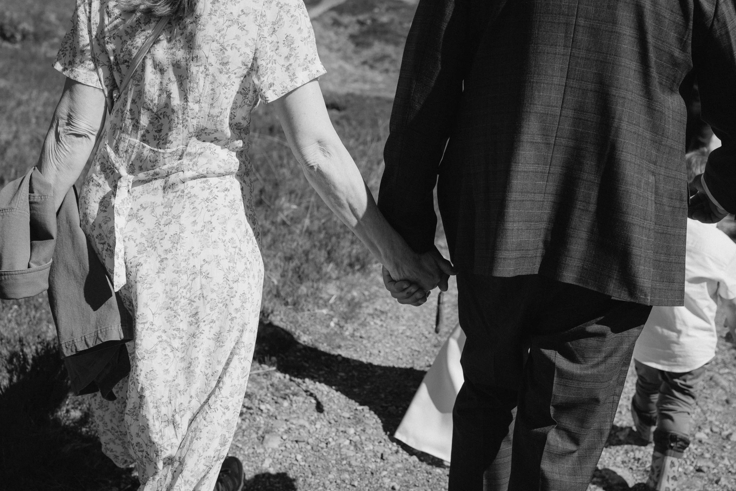 A black and white photo of an elderly woman and a man holding hands and walking outdoors. - captured by an Edinburgh wedding photographer
