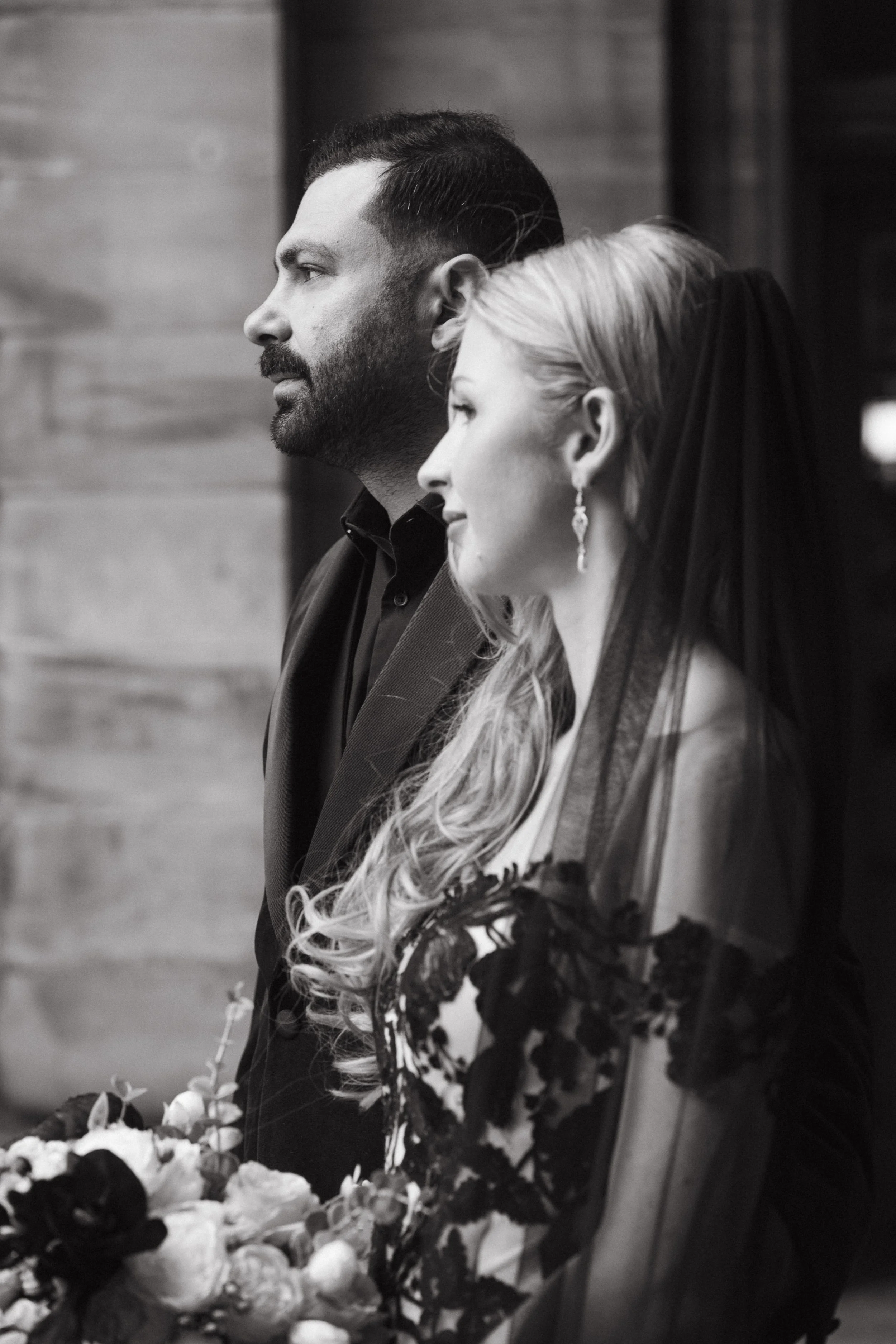 A black-and-white photo of a bride and groom standing side by side during a wedding ceremony, facing forward. - captured by an Edinburgh wedding photographer