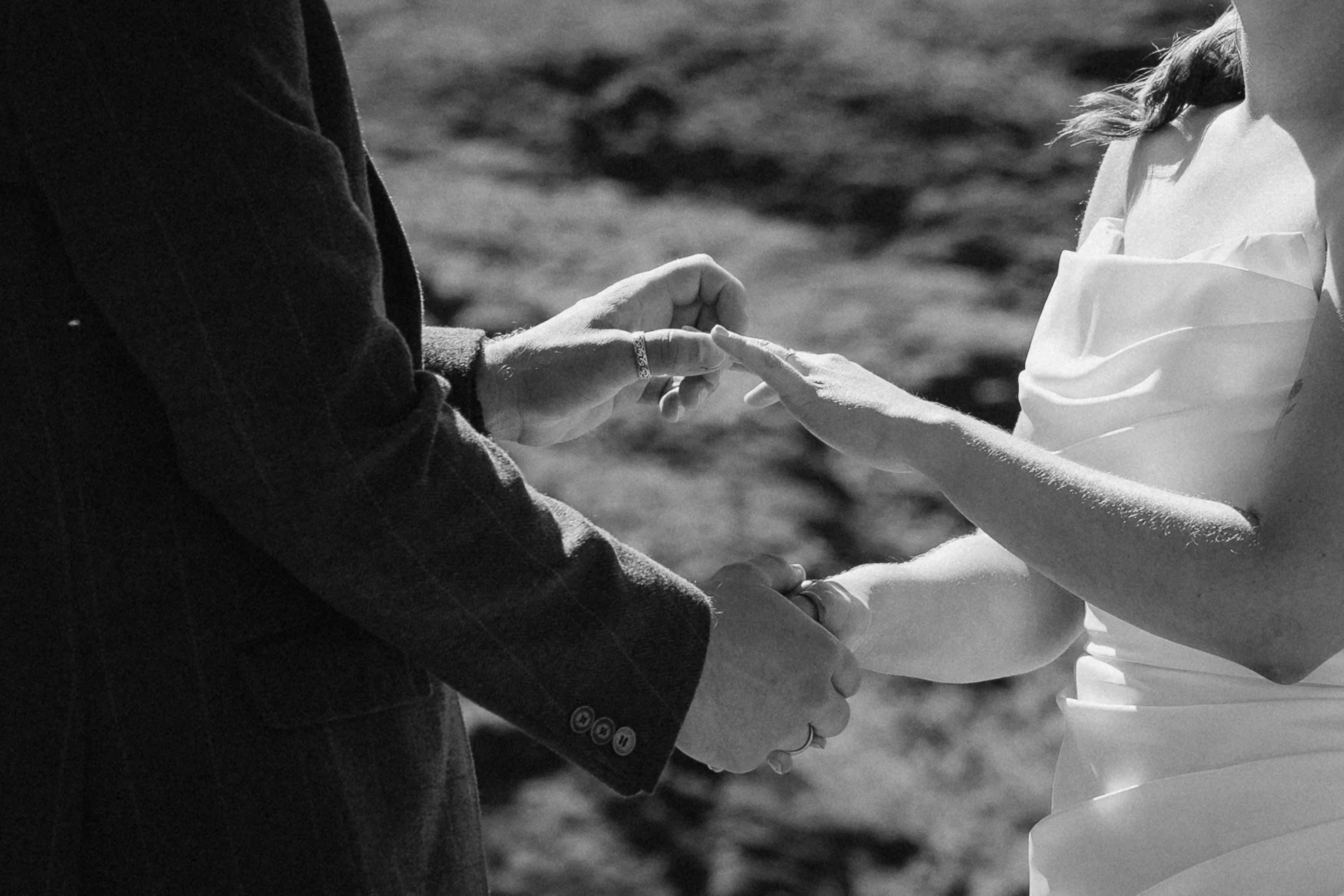 Close-up of a couple holding hands and touching fingers during a wedding ceremony outdoors. - captured by an Edinburgh wedding photographer