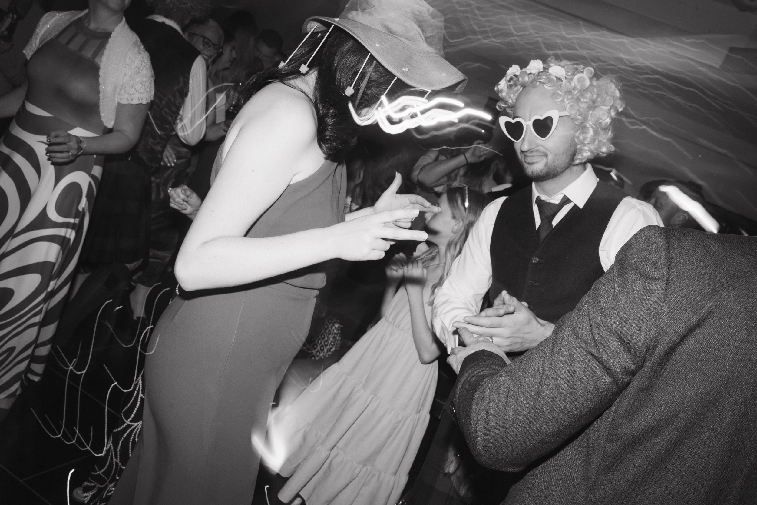 People at a party wearing funky sunglasses and costumes, dancing and socializing. - captured by an Edinburgh wedding photographer