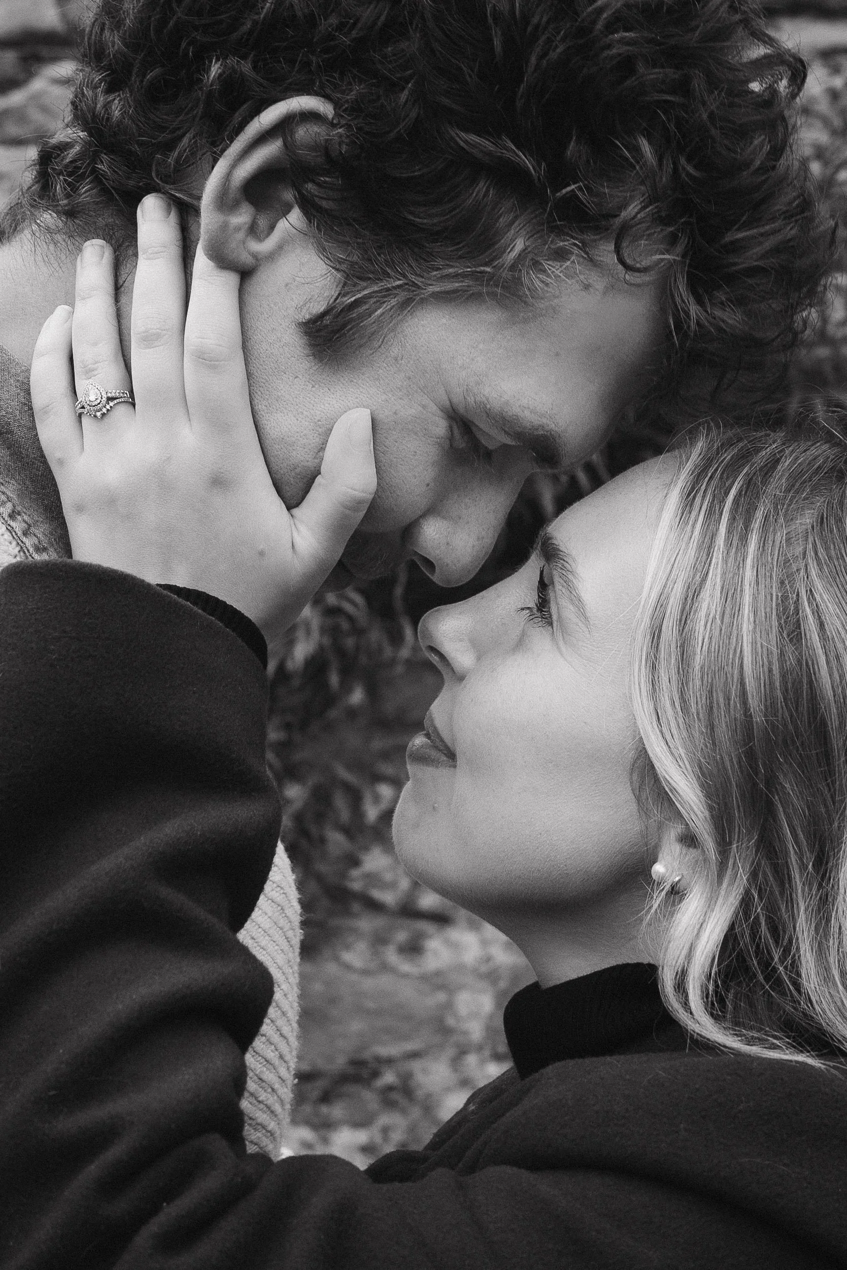 A black-and-white photo of a man and woman with their foreheads touching and eyes closed, sharing an intimate moment outdoors. - captured by an Edinburgh wedding photographer