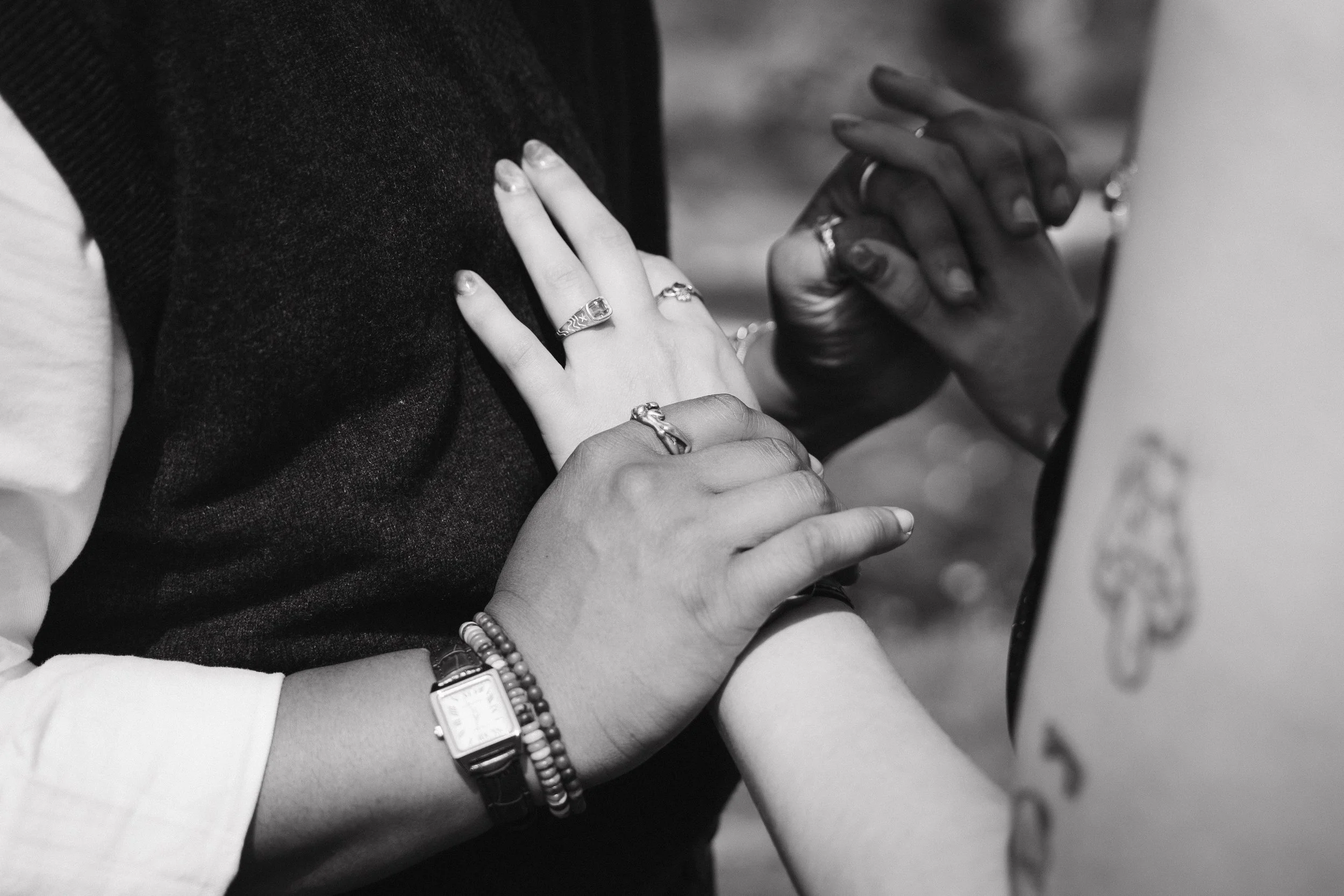 Two people holding hands during a ceremony, one wearing a watch and bracelets, and both with rings on their fingers - captured by an Edinburgh wedding photographer