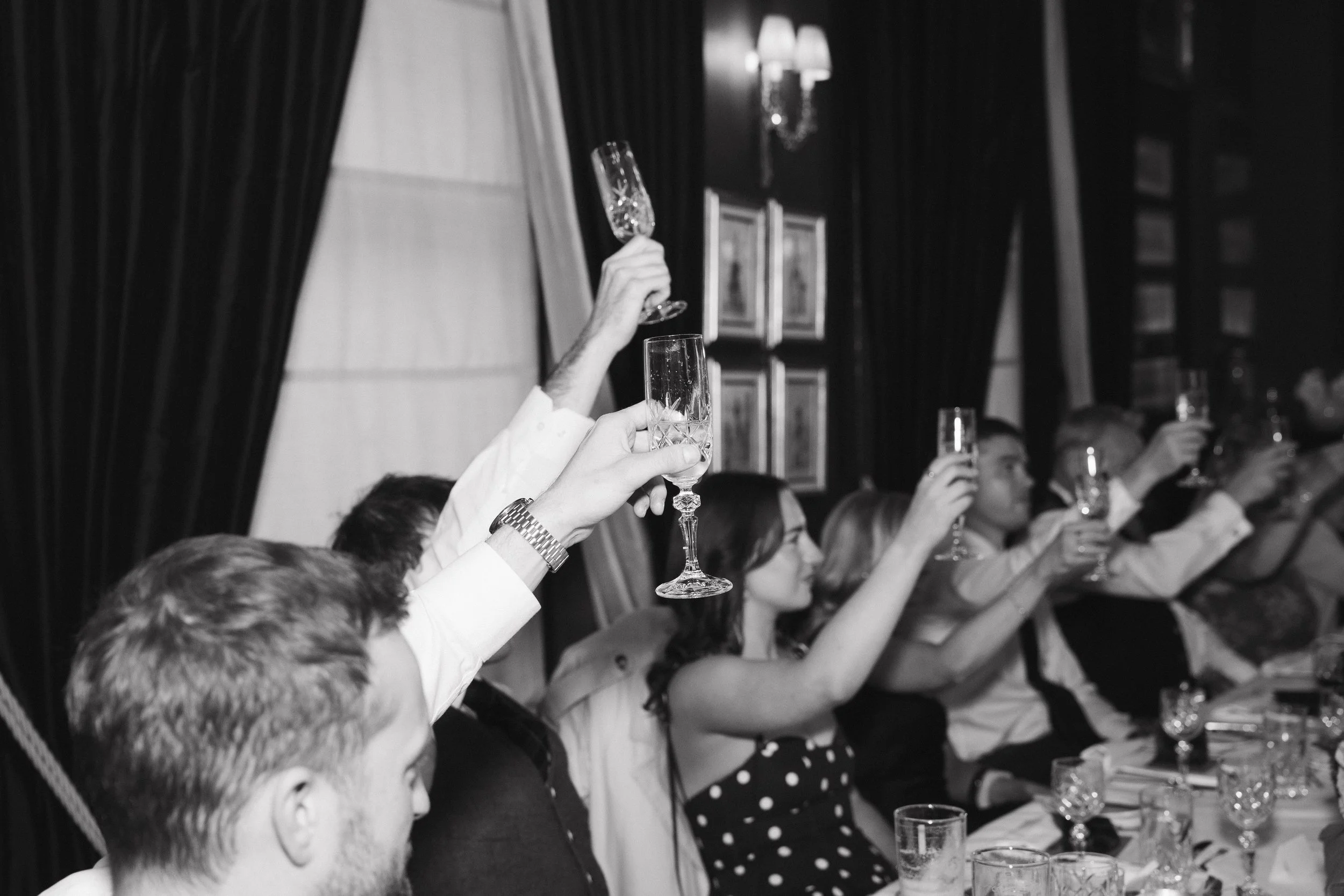 People raising champagne glasses in a toast during a formal celebration at a dinner table. - captured by an Edinburgh wedding photographer