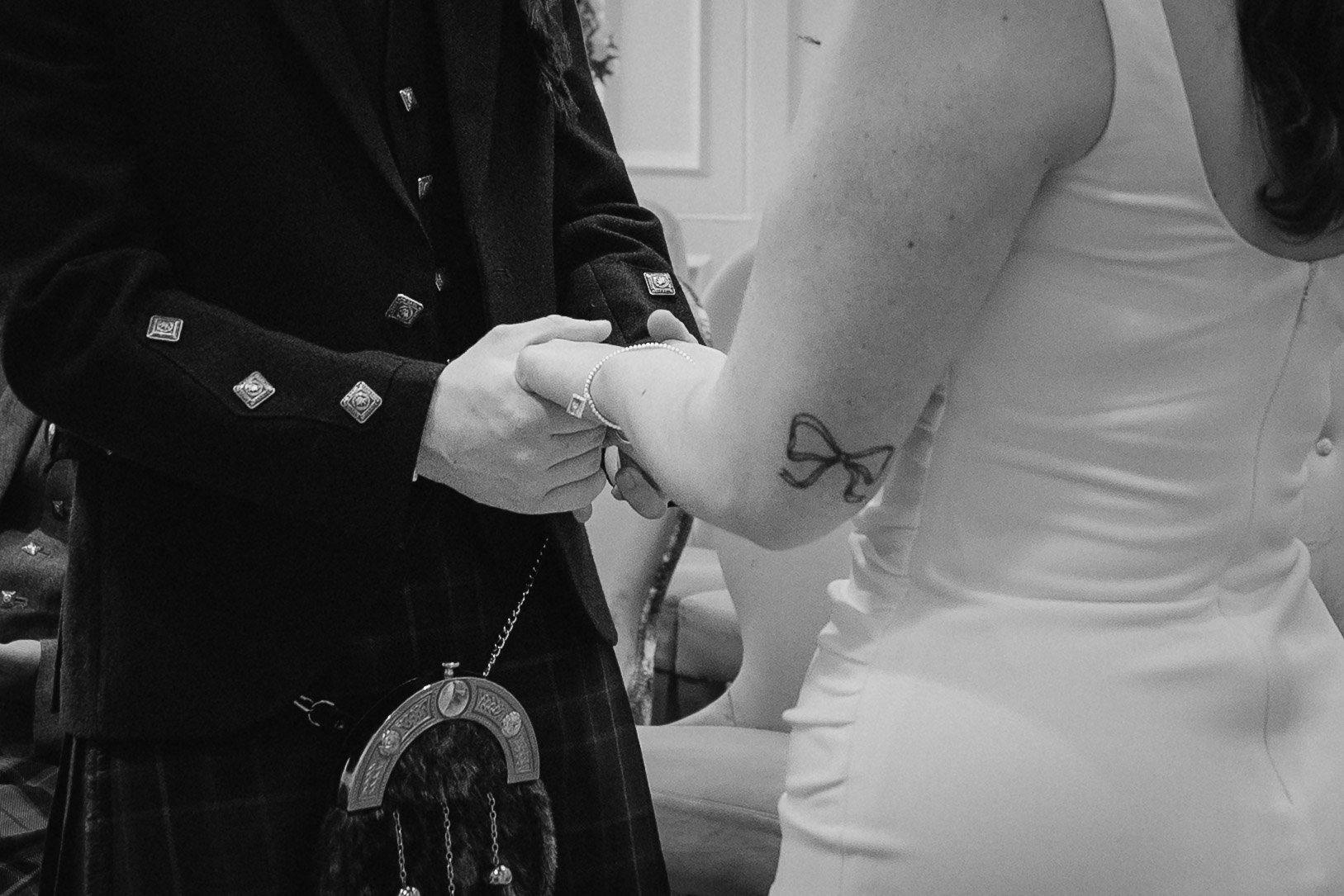 A person in a white dress getting married, holding another person's hand in an indoor setting. - captured by an Edinburgh wedding photographer