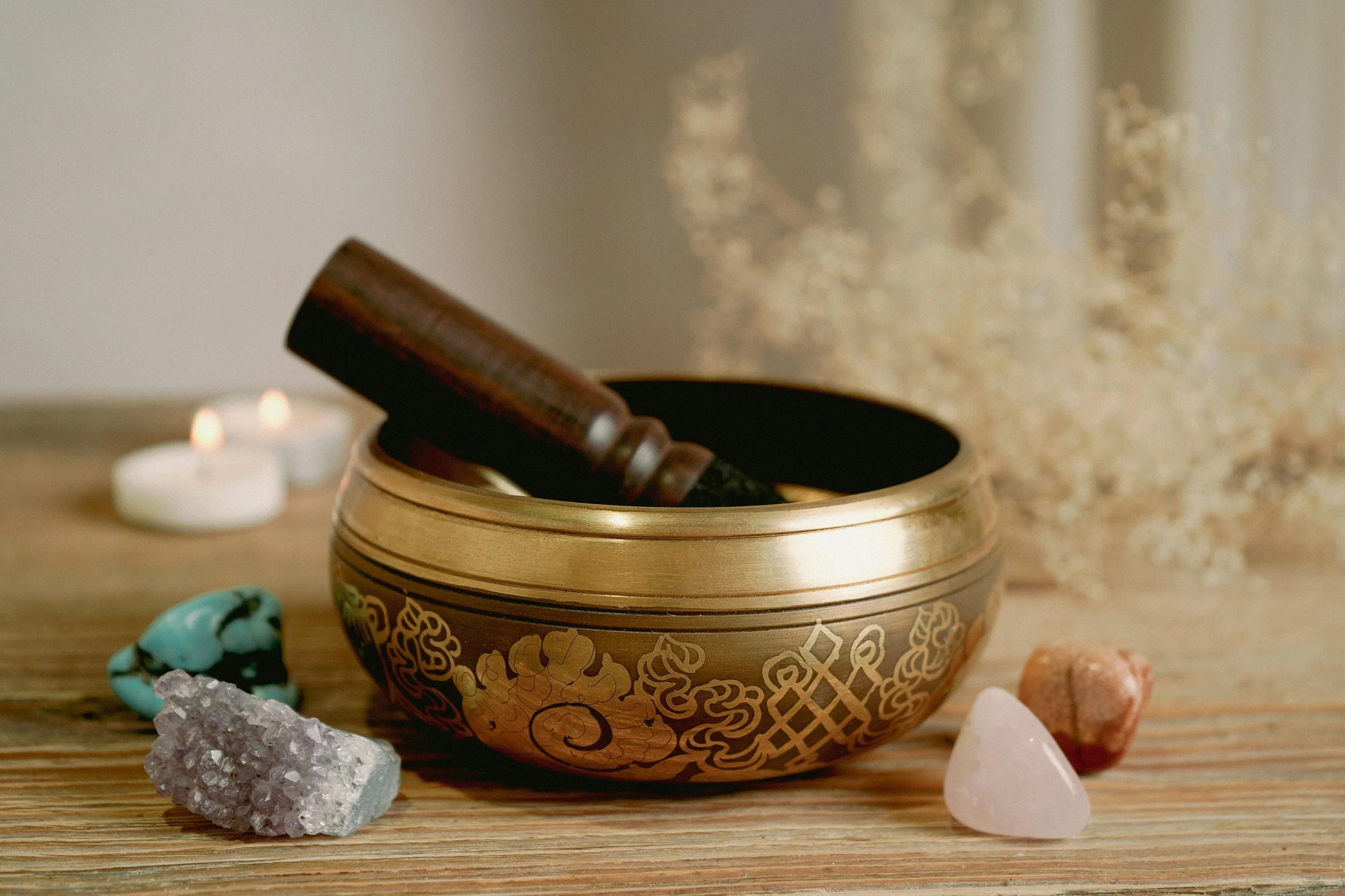 Crystals arranged for care and cleansing, around a tibetan bowl surrounded by natural elements and soft light.