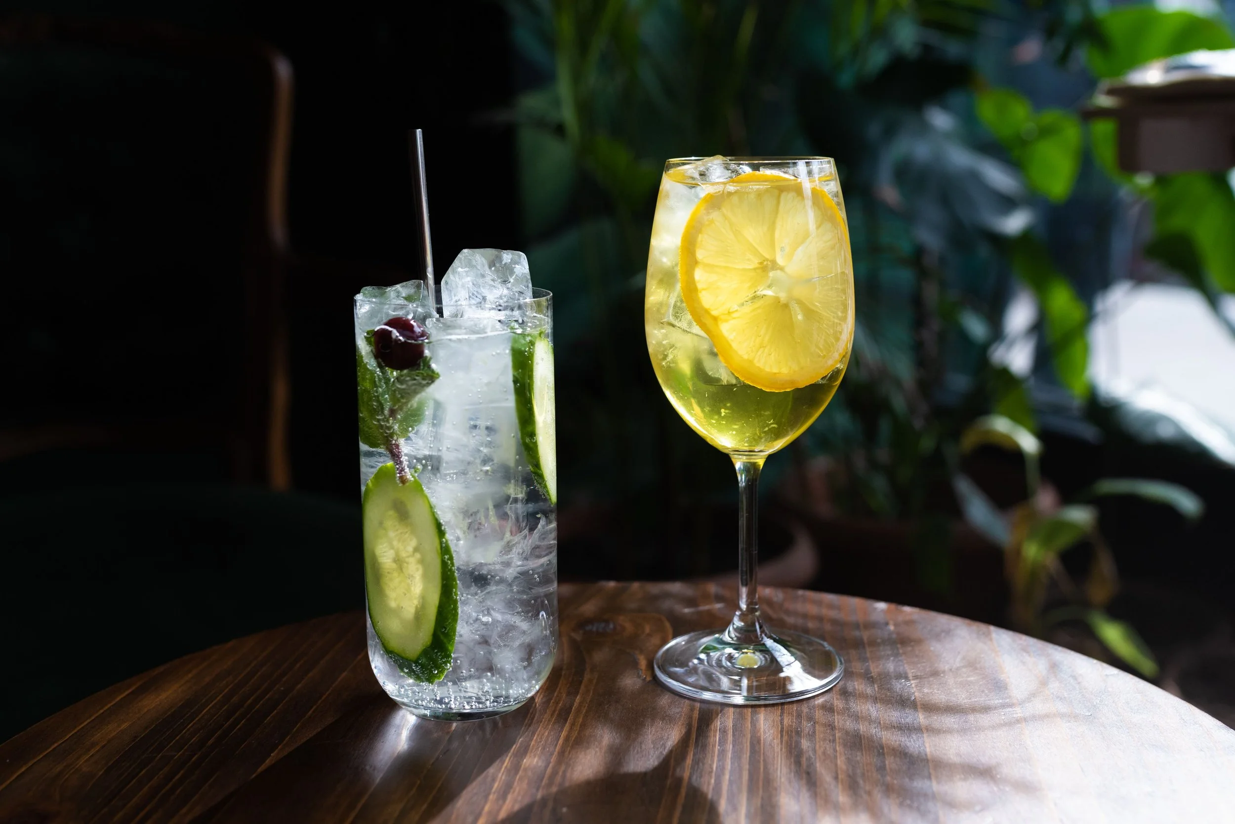 De l'eau rafraîchissante aromatisée au concombre, au citron et à la menthe, servie dans deux verres posés sur une table en bois.