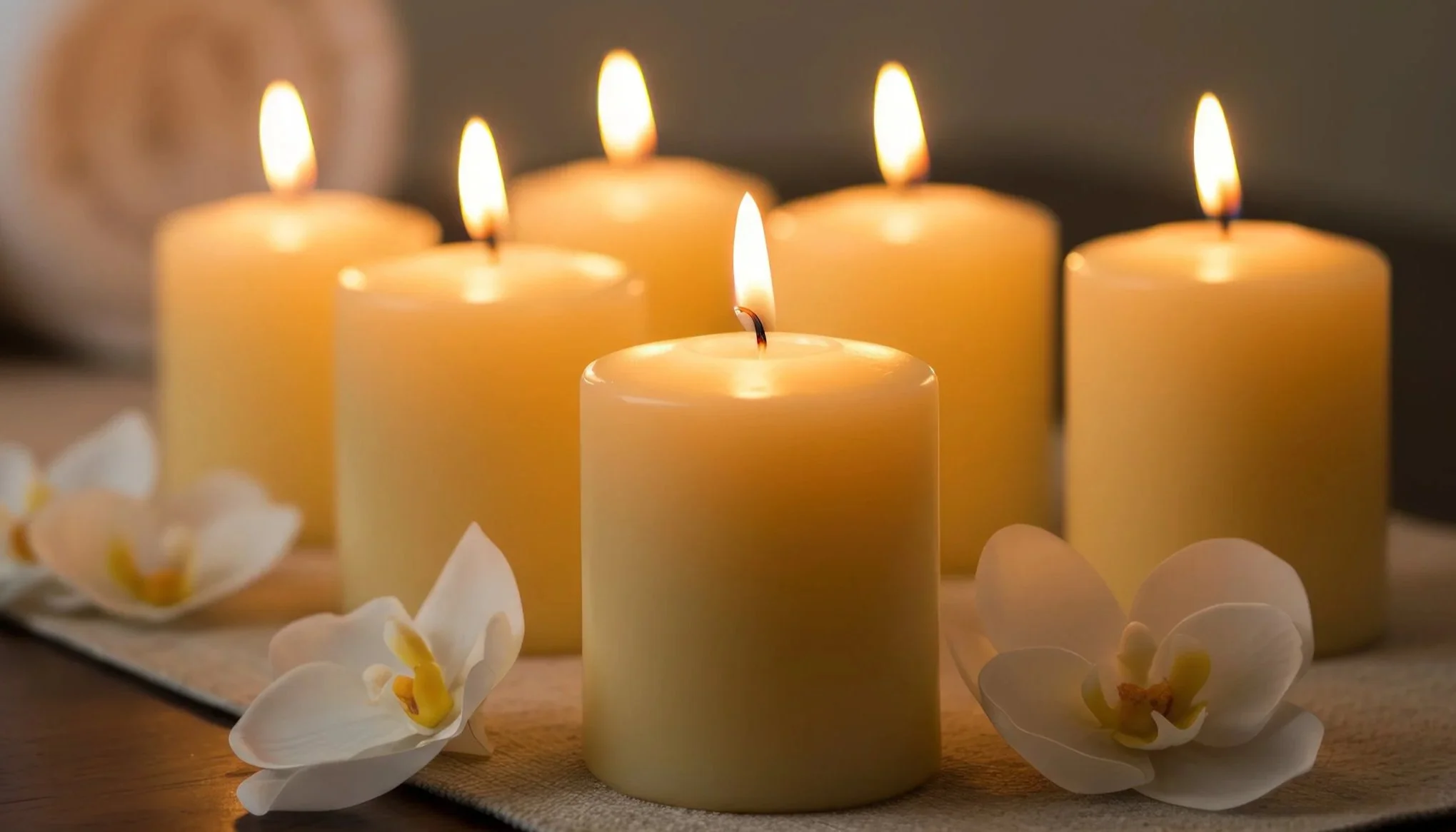 Lit candles and Tahitian gardenia flowers creating a warm, calming atmosphere for an energy healing session.
