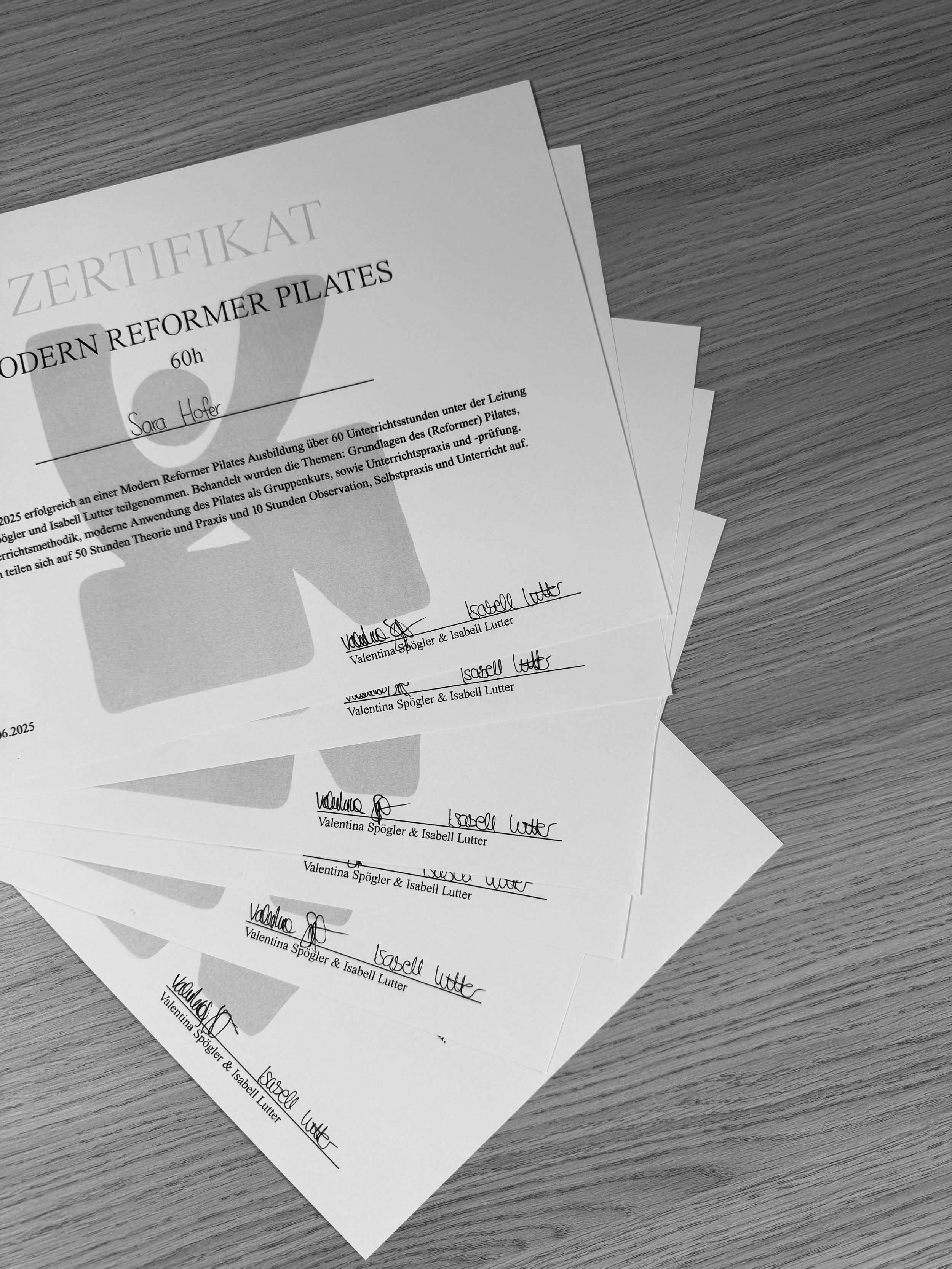 Mehrere gefälschte Ausbildungszertifikate für Pilates auf einem Tisch, mit handschriftlichen Unterschriften und Stempeln.