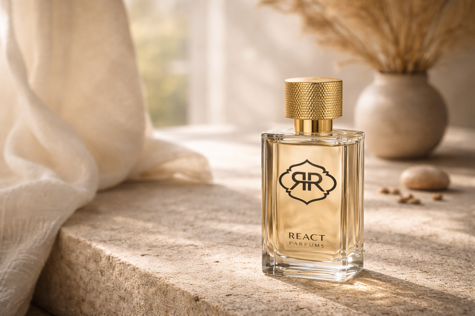 A clear glass perfume bottle with a gold textured cap and a black logo, placed on a beige stone surface, with a decorative vase and pebbles in the background.