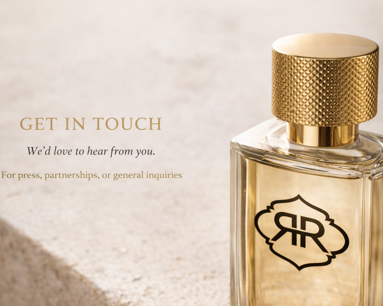 A perfume bottle with a gold cap and black logo on clear glass, positioned on a light, textured surface, accompanied by text encouraging contact for inquiries.