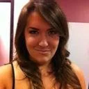 A young woman with long dark hair smiling at the camera, wearing a sleeveless top.